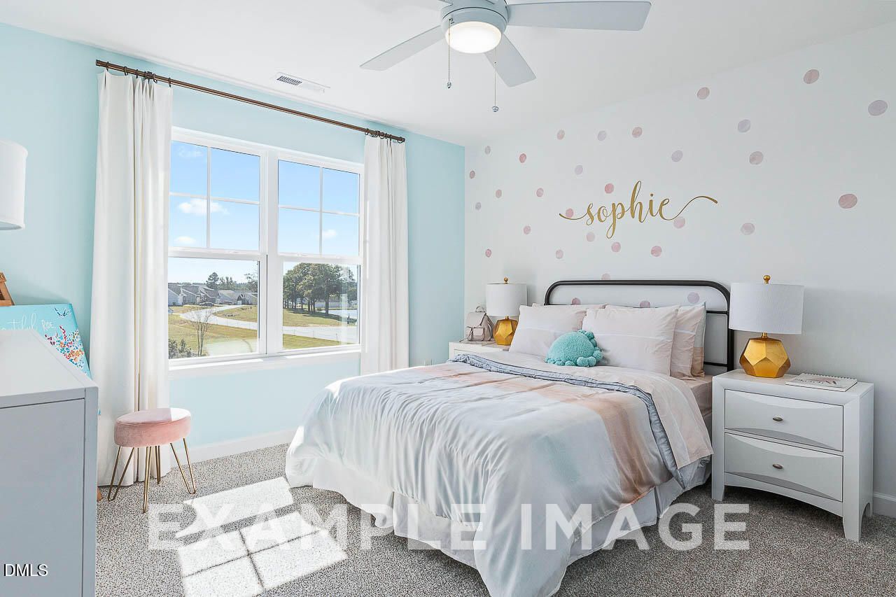 Bright bedroom with mint accent walls, white bedding, ceiling fan, and neighborhood views in Davidson Homes Ash C plan, Lillington NC