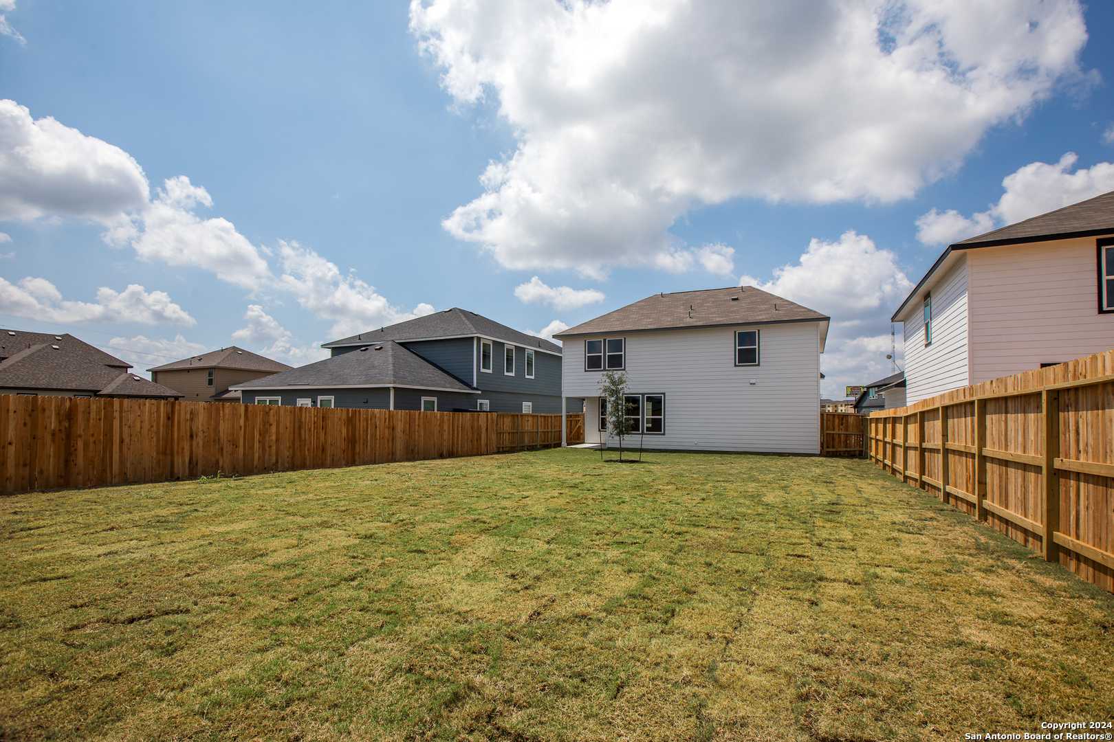 Private backyard with lush green lawn, wooden fence, and covered patio in Davidson Homes The Murray H, Seguin, Texas