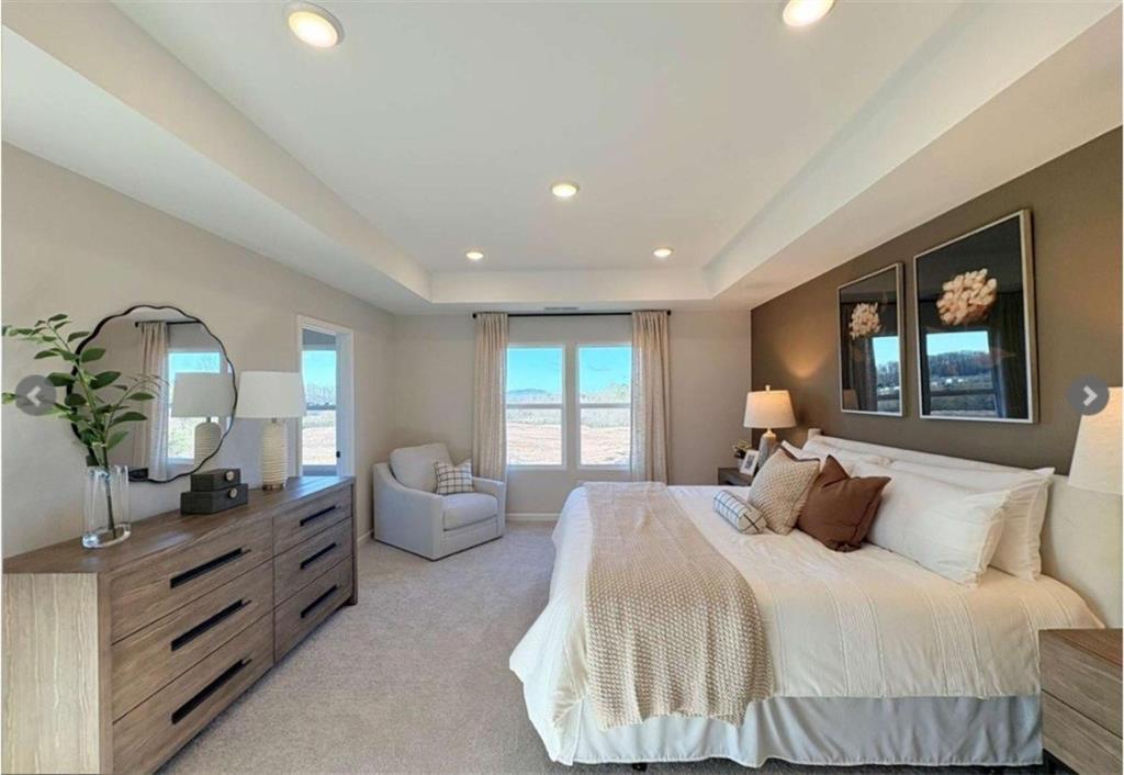 Spacious master bedroom with king bed, beige accents, large window, and modern dresser in Davidson Homes The Durham D, Cumming, GA