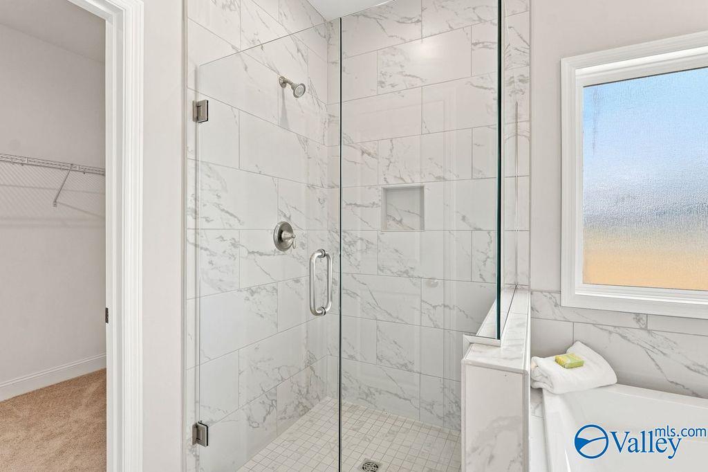 Frameless glass walk-in shower with marble tile and soaking tub in master bath of Davidson Homes The Harrison, Hartselle AL