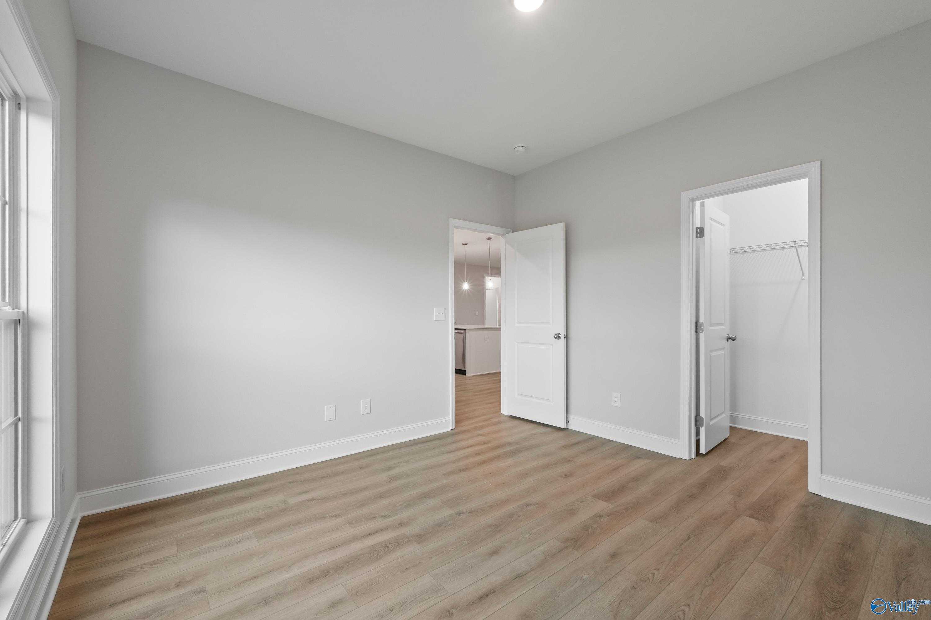 Spacious bedroom with gray walls, hardwood floors, walk-in closet, and en-suite bath in Davidson Homes The Lanier, Harvest, Alabama