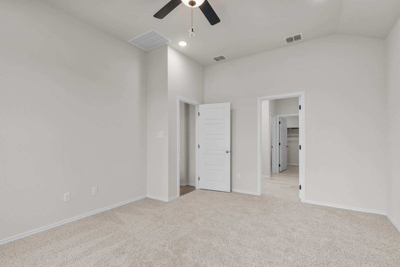 Spacious bedroom with neutral carpet in The Sequoia C floor plan by Davidson Homes in Converse, Texas.