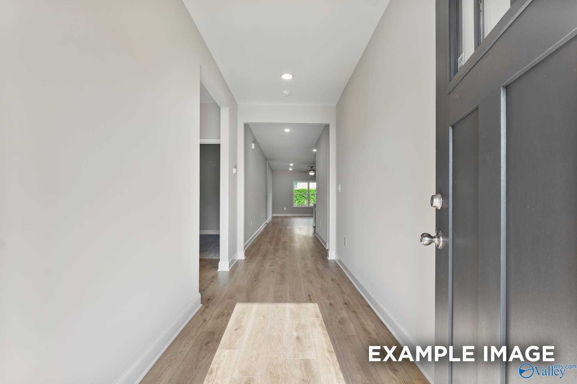 Bright hallway with light oak floors, neutral walls, recessed lights, and glass-front door in Davidson Homes The Daphne C, New Market, Alabama
