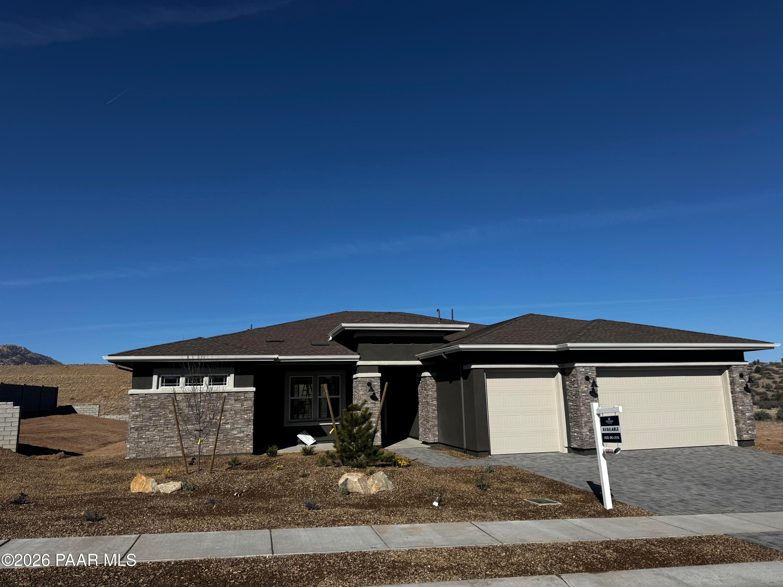 Modern 1-story 3-bedroom home with 3-car garage, stone facade, and desert landscaping in Hidden Hills, Prescott, Arizona