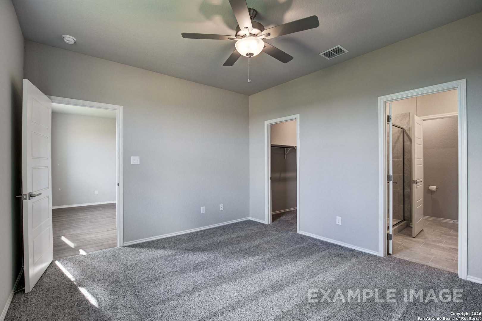 Spacious master bedroom with ceiling fan, walk-in closet, and en-suite bath in Davidson Homes The Frio B, San Antonio, Texas