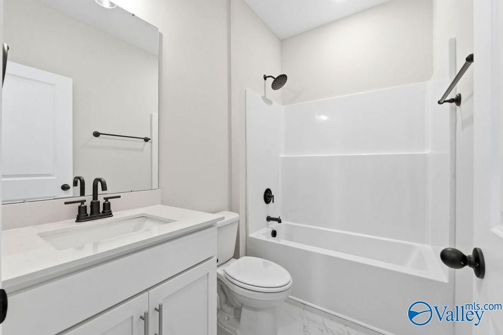 Bright bathroom with white tub-shower combo, modern vanity sink, toilet in Davidson Homes The Montgomery B, Hartselle, Alabama