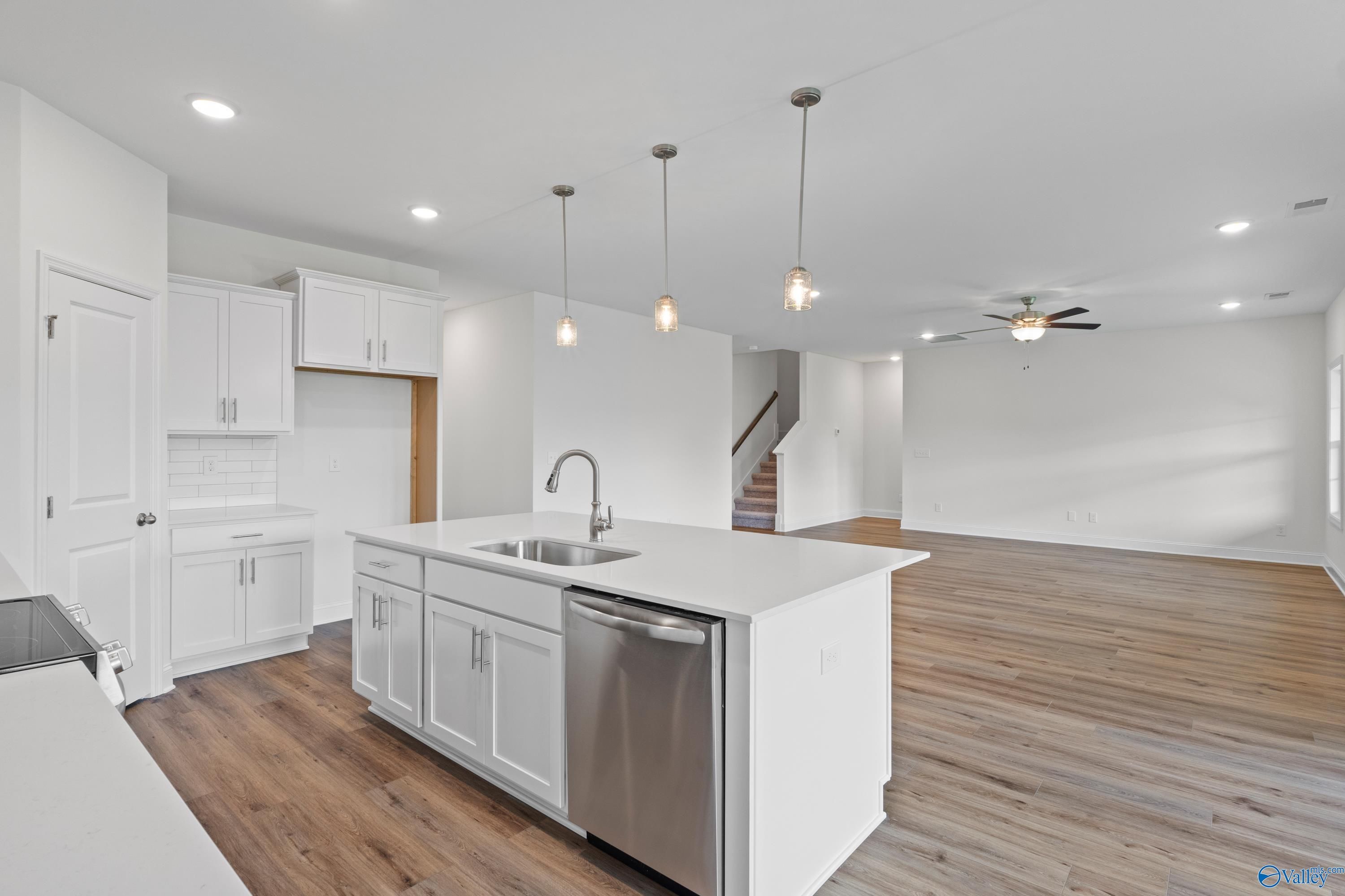 Modern open-concept kitchen with white shaker cabinets, quartz island sink, stainless appliances in Davidson Homes The Rockford B, Toney, AL