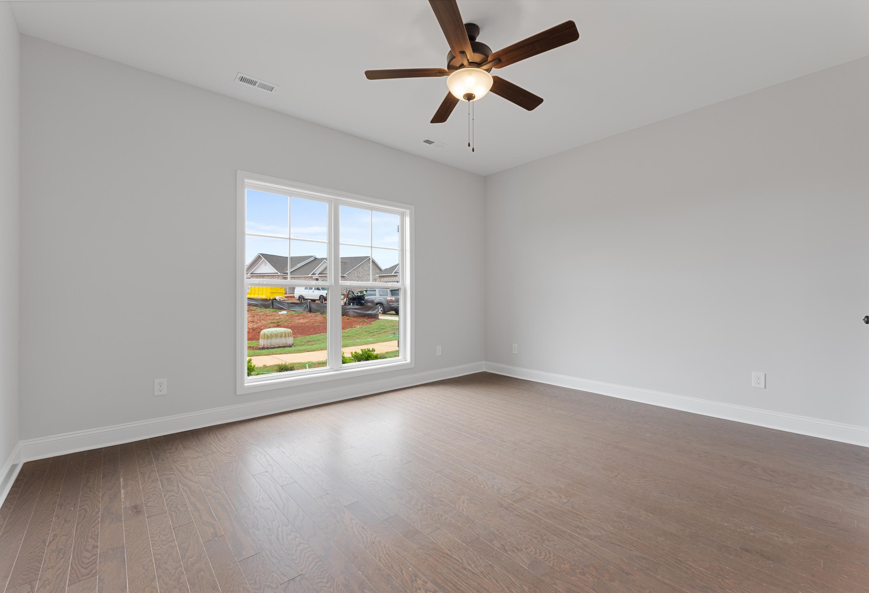 Spacious master bedroom in The Copeland with large windows, ceiling fan, hardwood floors overlooking Madison, Alabama neighborhood
