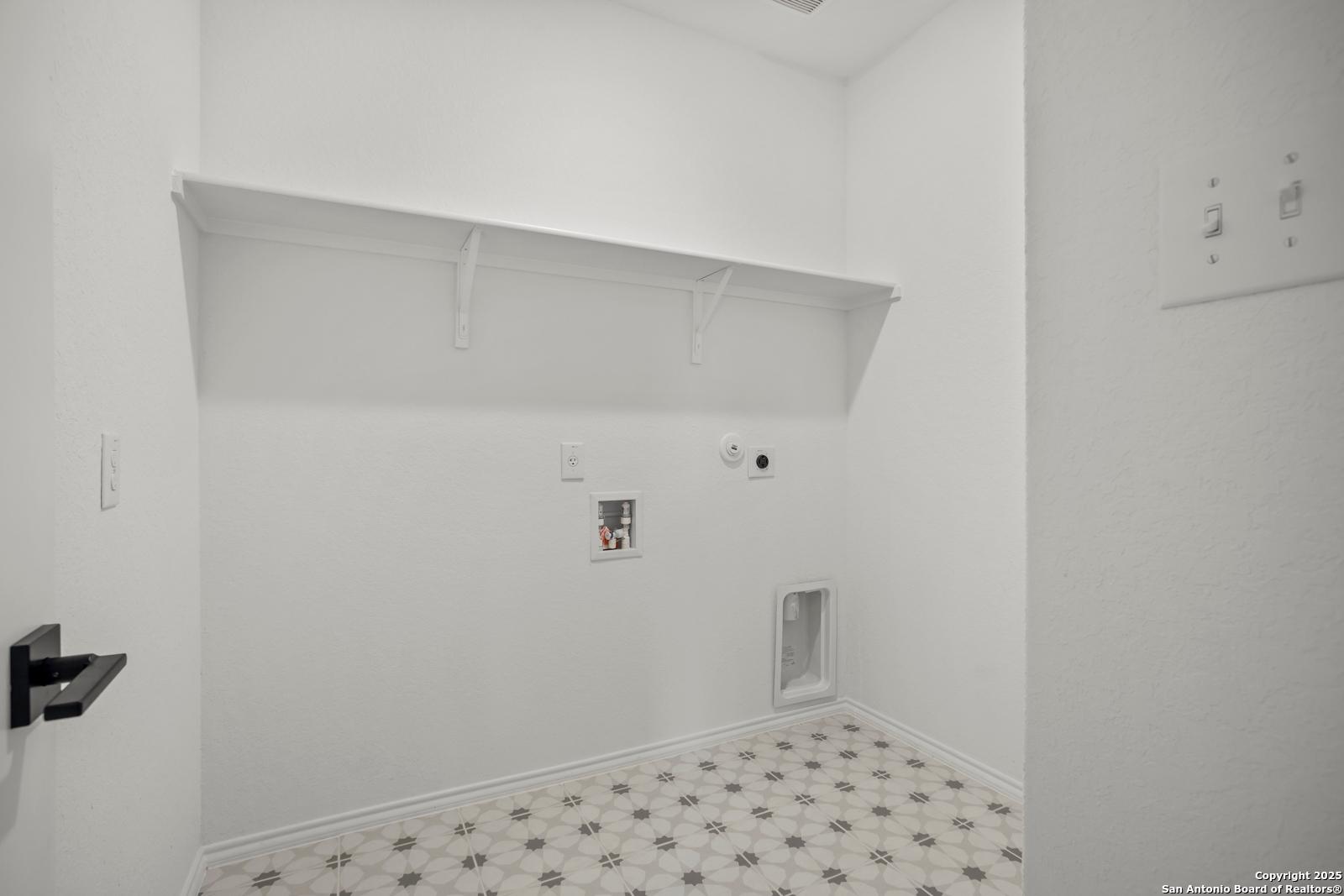 Bright white laundry room with built-in shelves, washer-dryer hookups, pet door in The Daphne K, Davidson Homes, San Antonio
