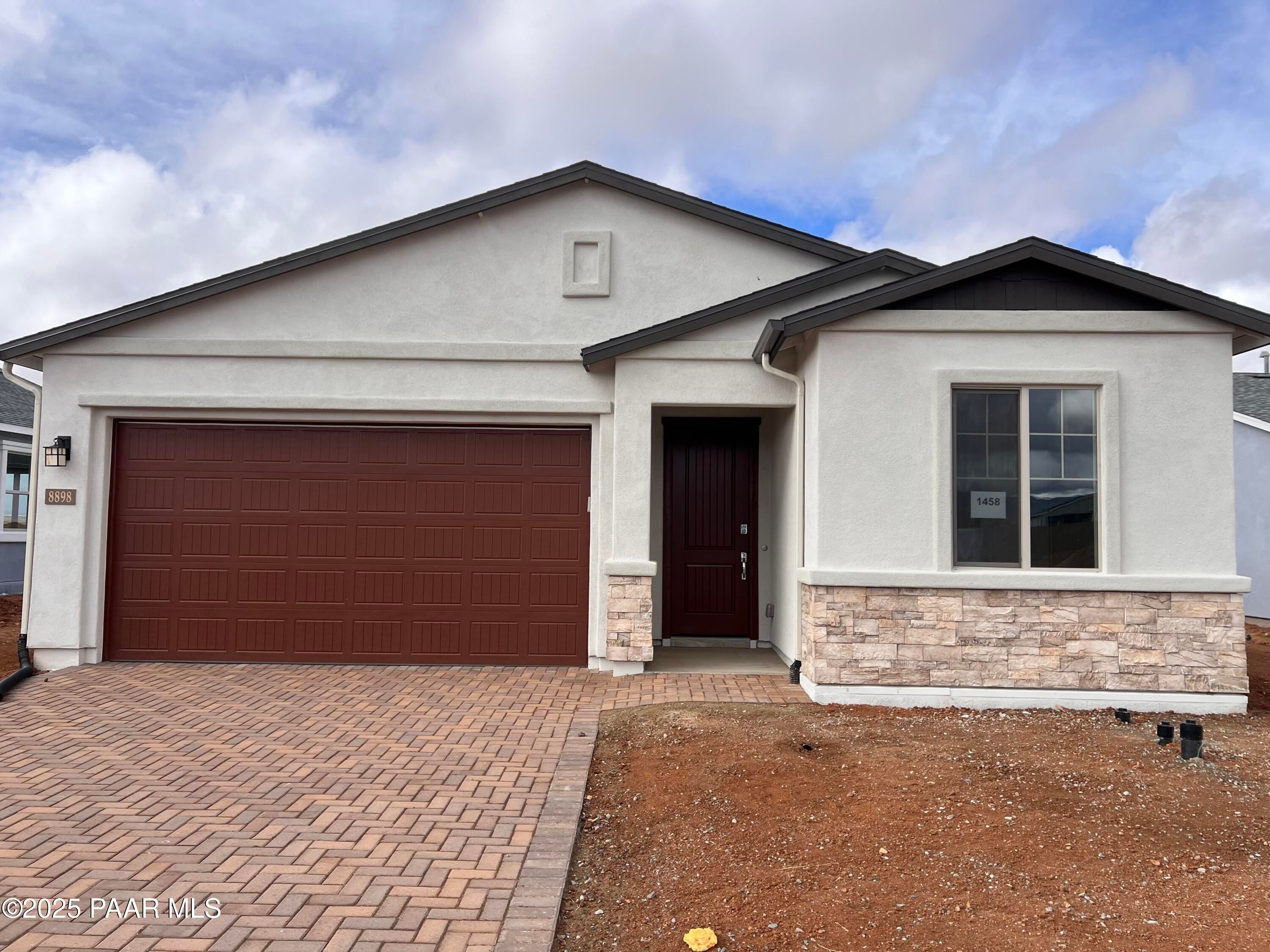 Modern single-story home with 3-car garage, stone accents, and paver driveway in North Ridge at Pronghorn Ranch, Prescott Valley, Arizona