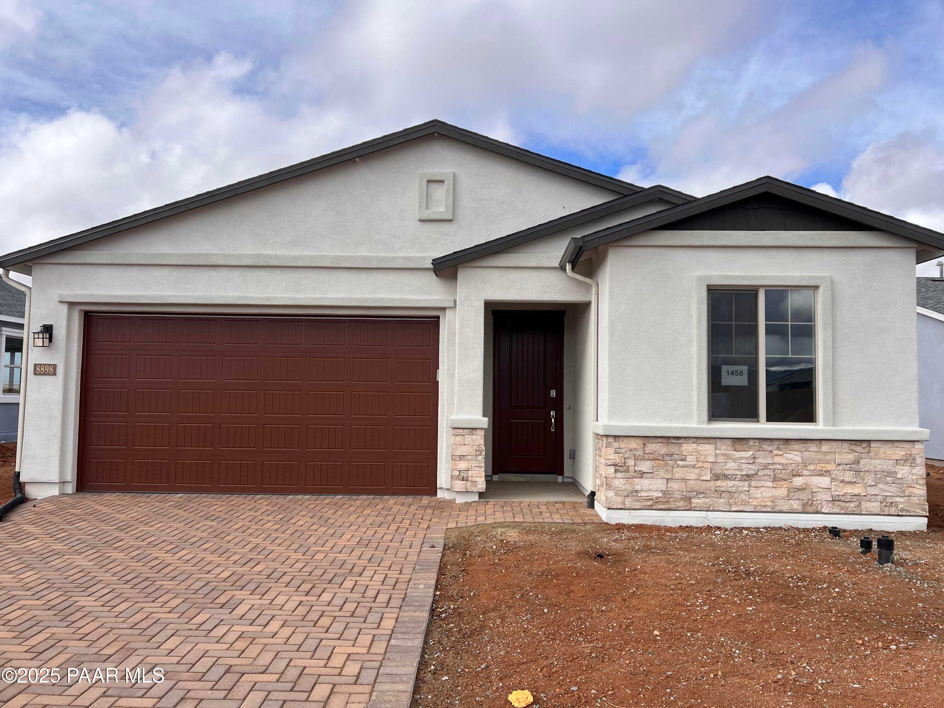 Modern single-story home with 3-car garage, stone accents, and paver driveway in North Ridge at Pronghorn Ranch, Prescott Valley, Arizona