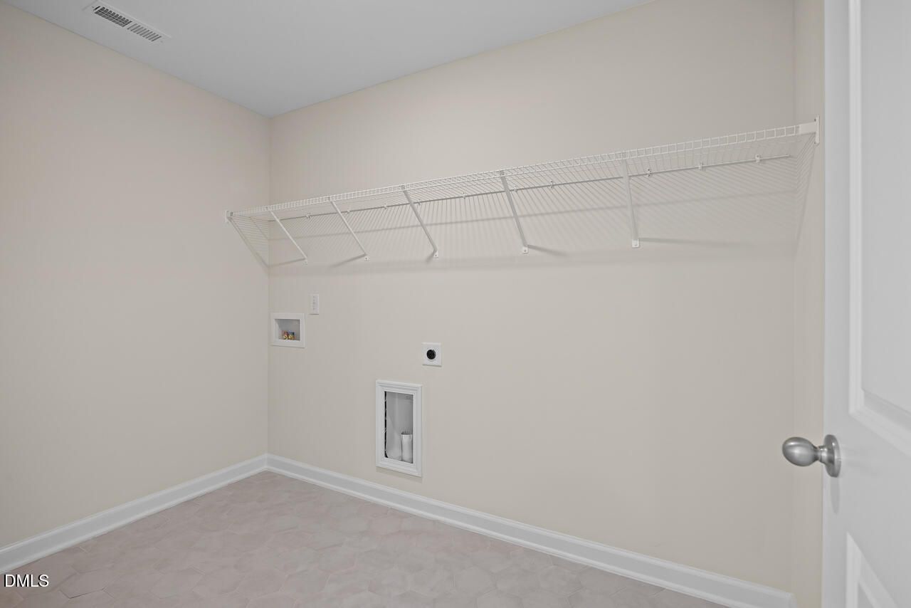 Spacious laundry room with wire shelving, hex tile flooring, and washer connections in Davidson Homes The Willow C, Zebulon, NC