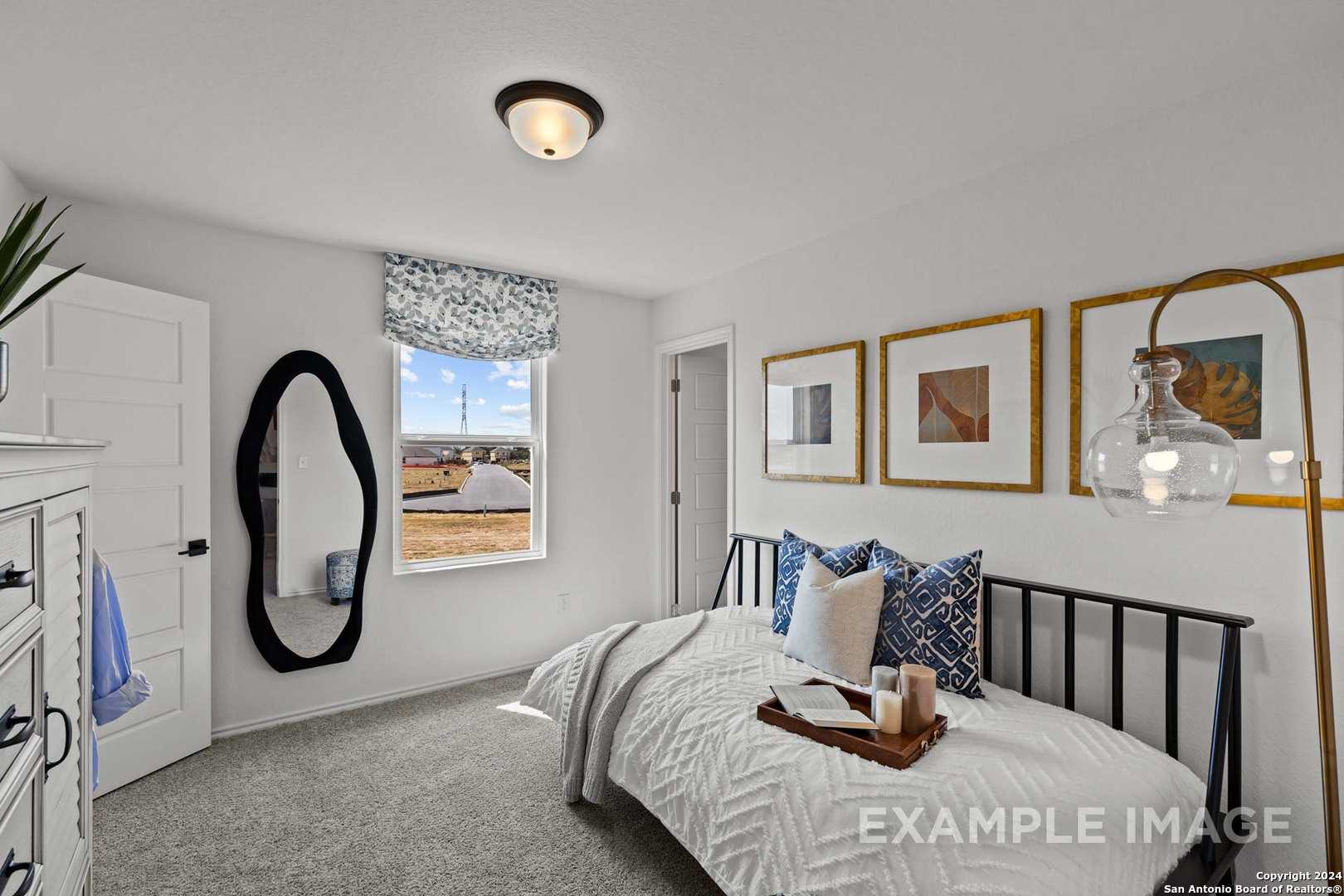 Cozy secondary bedroom with twin bed, black metal frame, large oval mirror, and window view in The Douglas G by Davidson Homes, Bricewood San Antonio