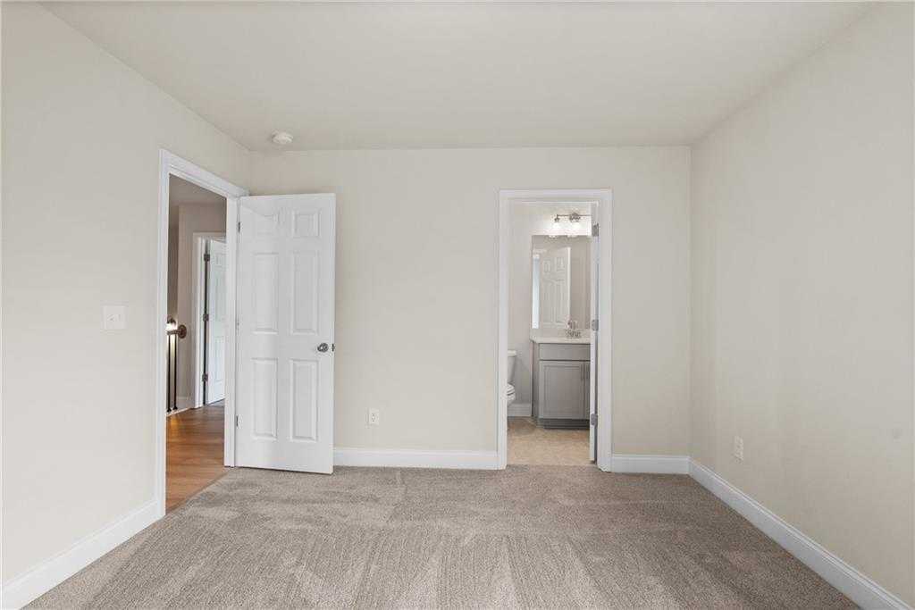 Bright secondary bedroom with attached bath, neutral walls, and carpet flooring in Davidson Homes The Hickory B at Wehunt Meadows, Hoschton