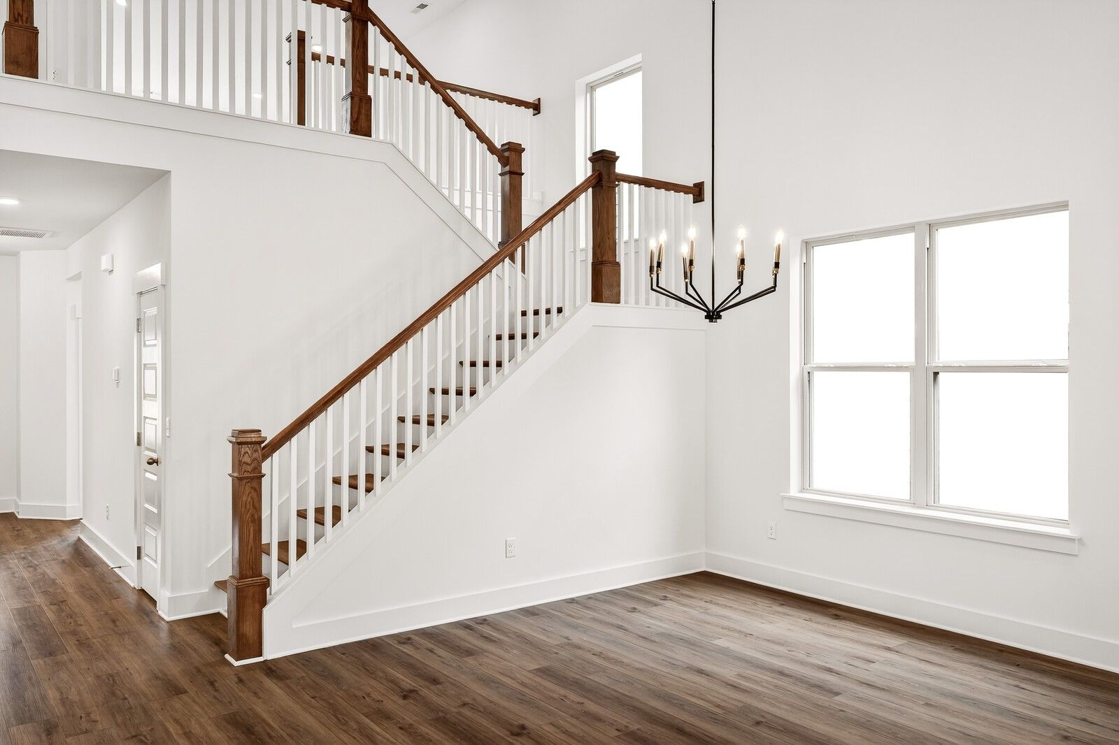 Elegant two-story wooden staircase with white balusters and chandelier in Davidson Homes Ridgeport C foyer, Gallatin, Tennessee