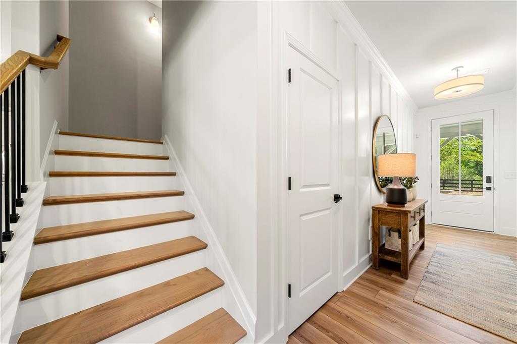 Bright entryway with oak staircase, shiplap walls, console table, and front door in Davidson Homes The Hickory B, Riverwood, Dallas, Georgia