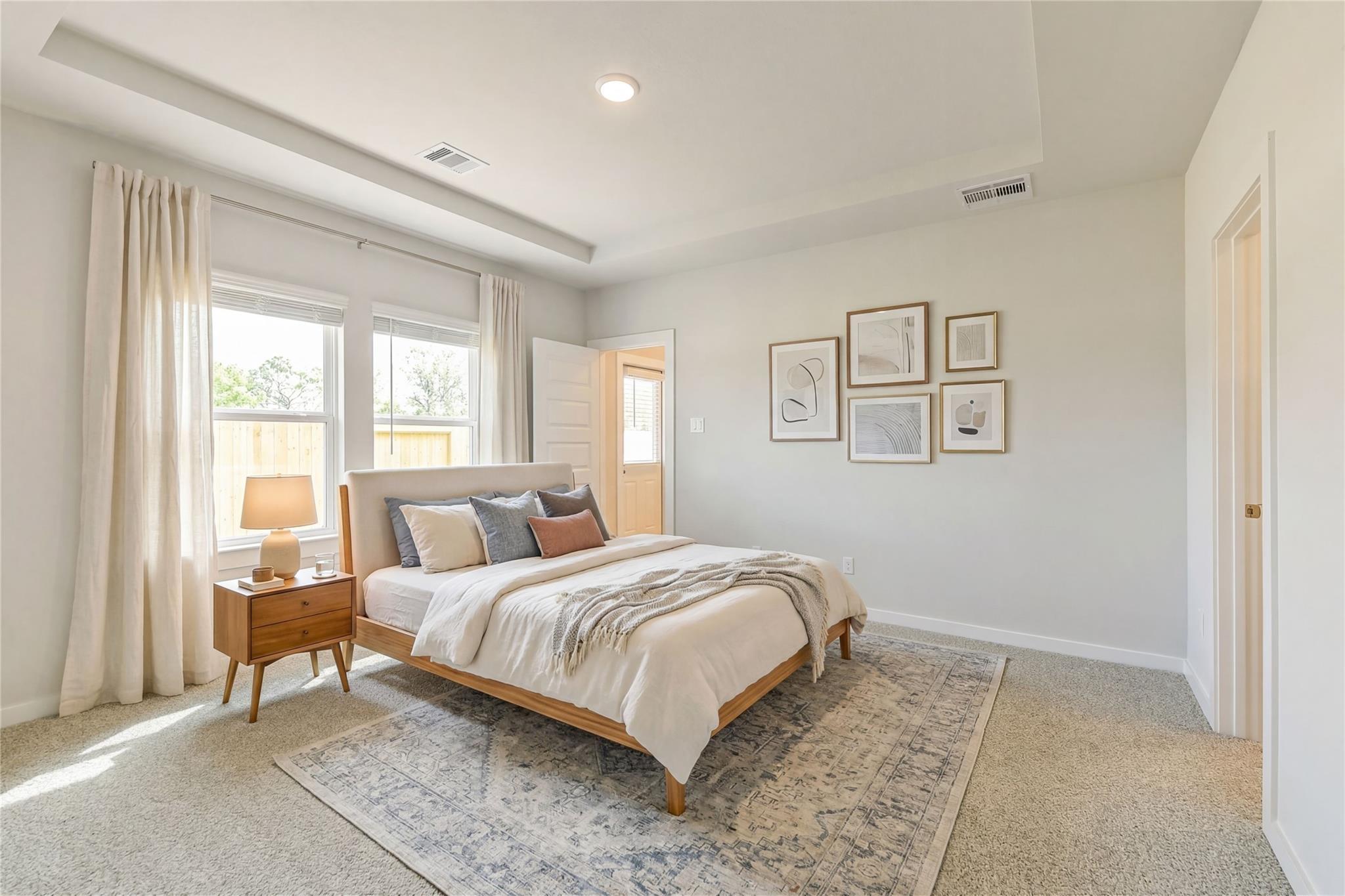 Elegant master bedroom with king bed, neutral bedding, sheer curtains, and wall art in Davidson Homes San Marcos E, Conroe Texas