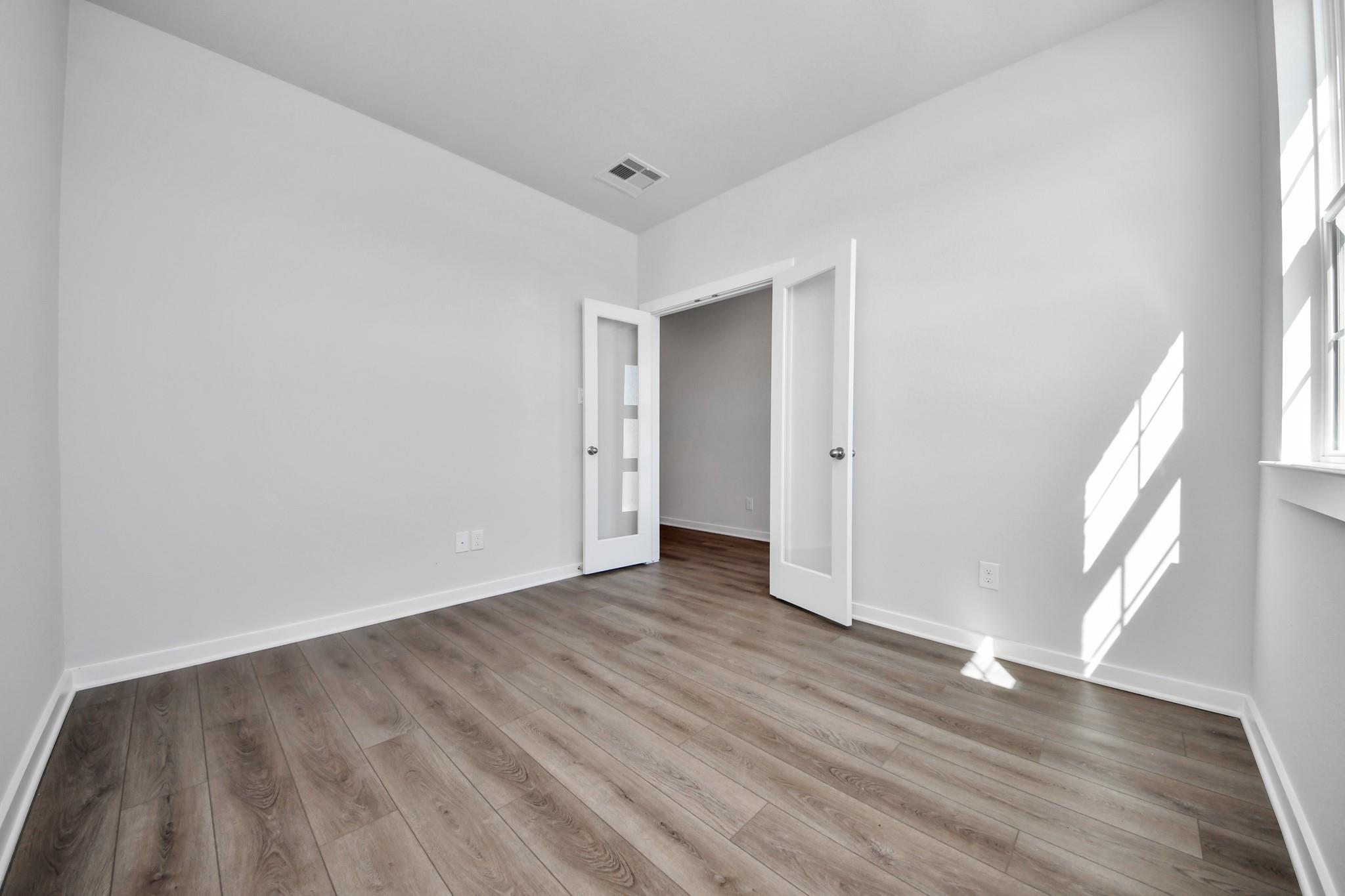 Bright flex room with luxury vinyl plank flooring and French doors in The Riviera A floor plan at Emberly, Beasley, TX.