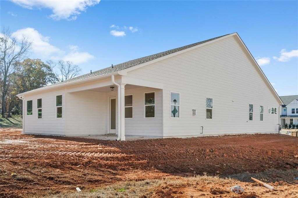 Side view of modern white single-story home with covered porch, windows, and 3-car garage in Wehunt Meadows, Hoschton, Georgia