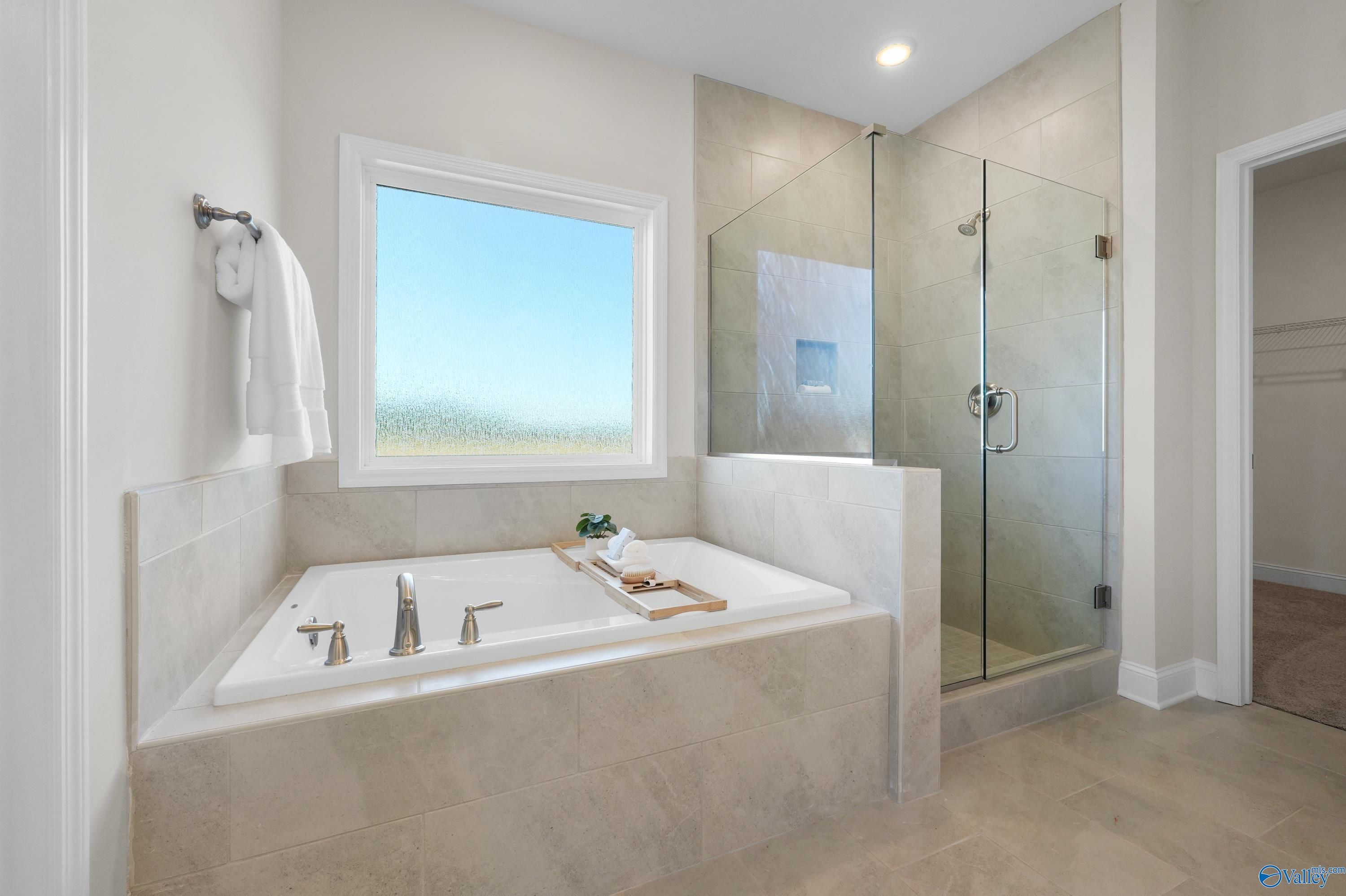 Elegant master bathroom with freestanding soaking tub, glass shower, and large window in Davidson Homes The Rockford B, Toney, Alabama