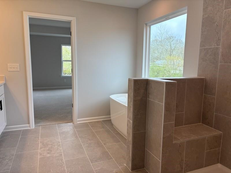 Luxurious master bathroom with freestanding tub, tiled floors, and garden view window in Davidson Homes The Hickory B, Winder, GA