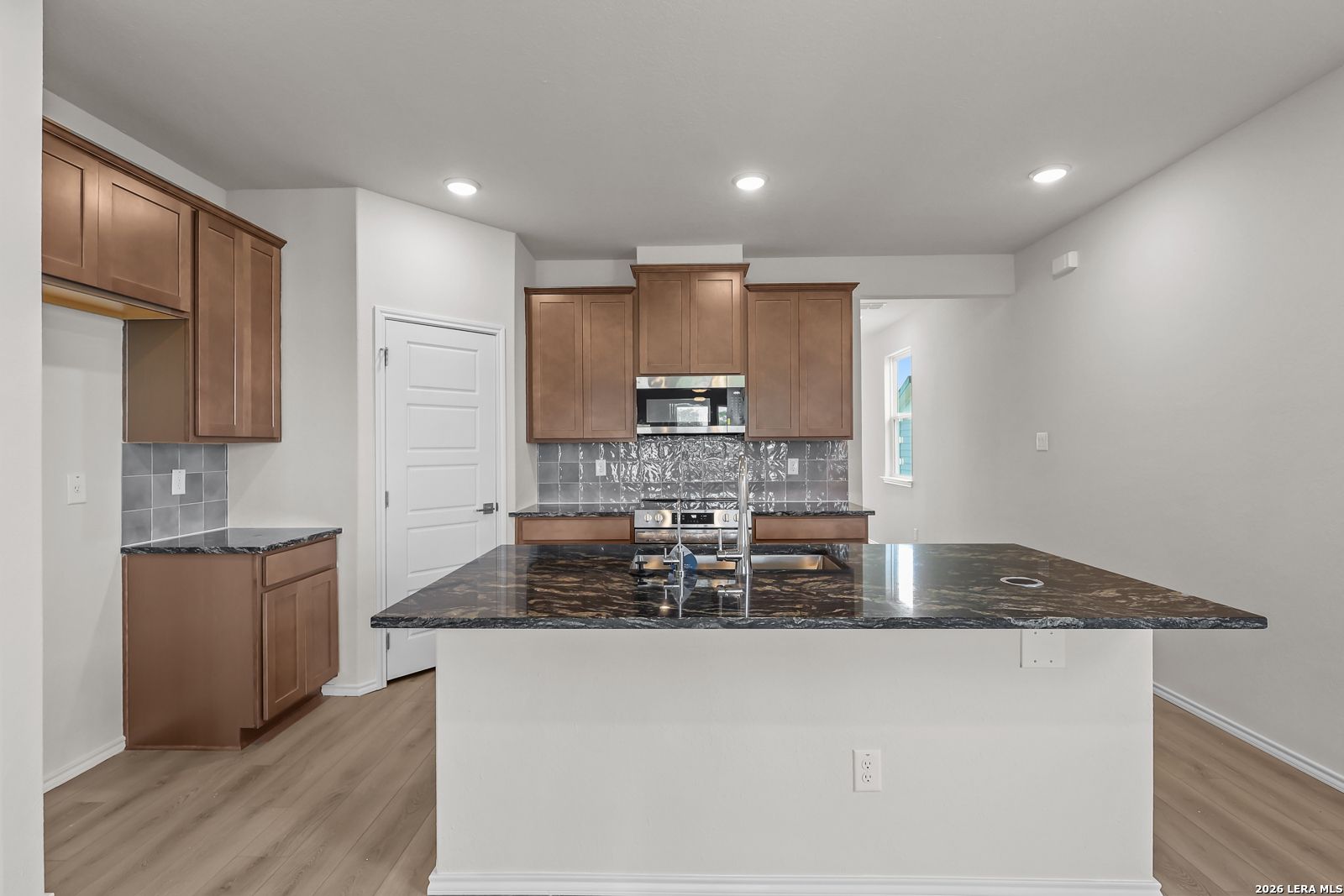 Modern kitchen with dark granite island and wood cabinets in The San Marcos F floor plan, Rayburn Valley, San Antonio.