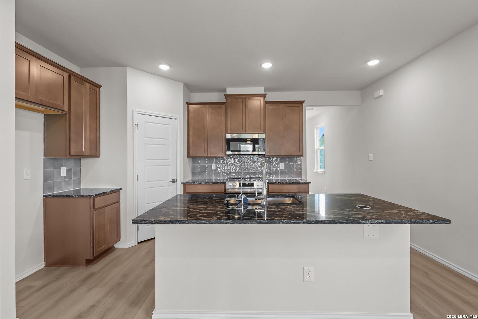 Modern kitchen with dark granite island and wood cabinets in The San Marcos F floor plan, Rayburn Valley, San Antonio.