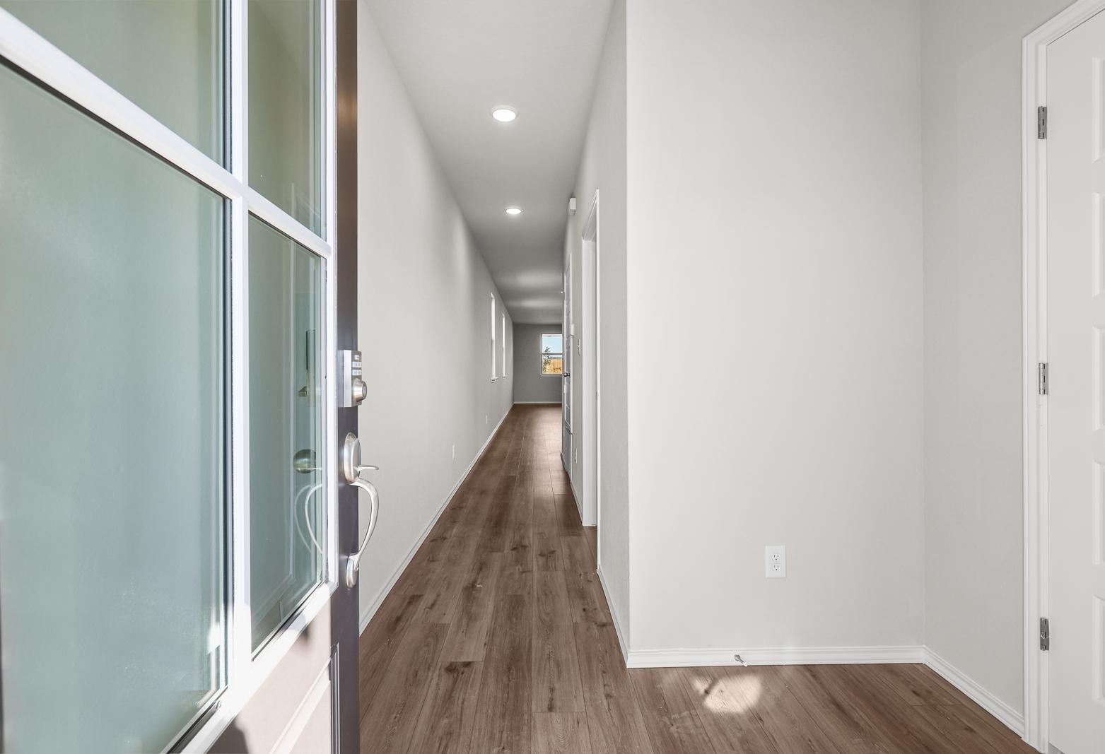 Bright entryway and long hallway with modern wood-style flooring in The Arroyo floor plan by Davidson Homes.