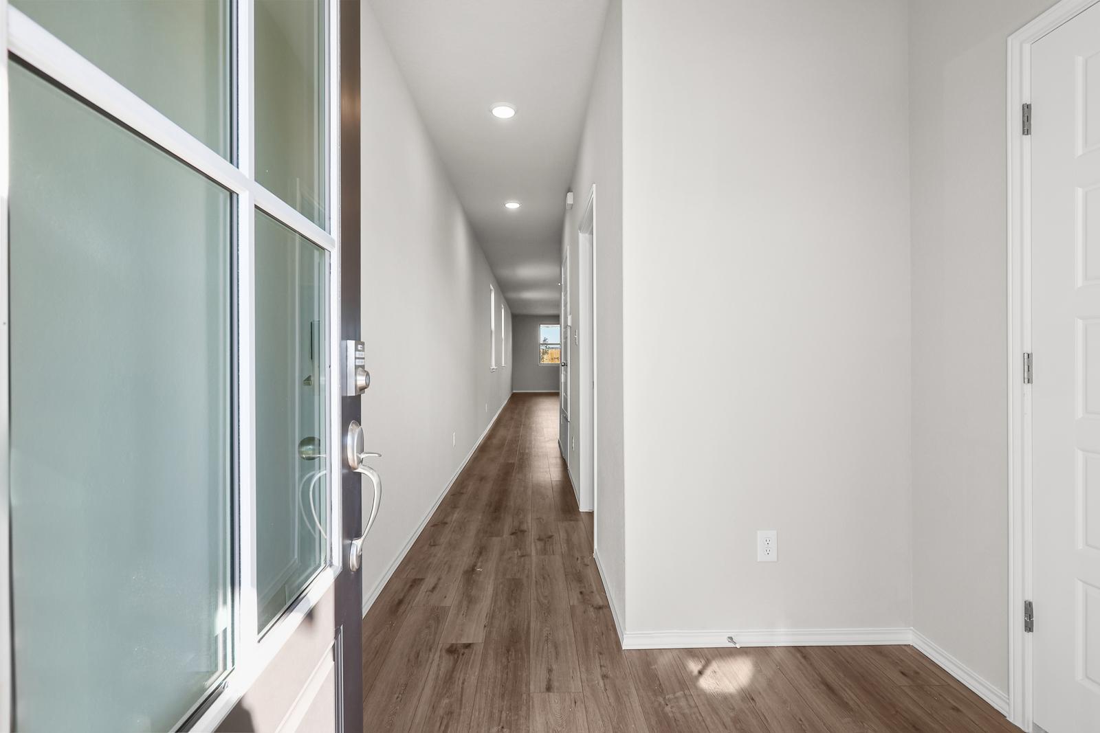 Bright entryway and long hallway with modern wood-style flooring in The Arroyo floor plan by Davidson Homes.