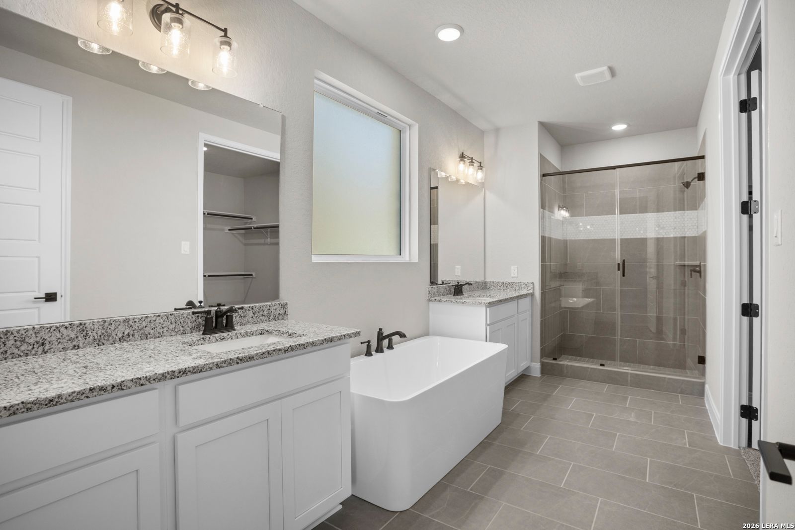 Modern primary bathroom with granite vanity, soaking tub, and glass shower in The Jennings G plan at Ladera, San Antonio.