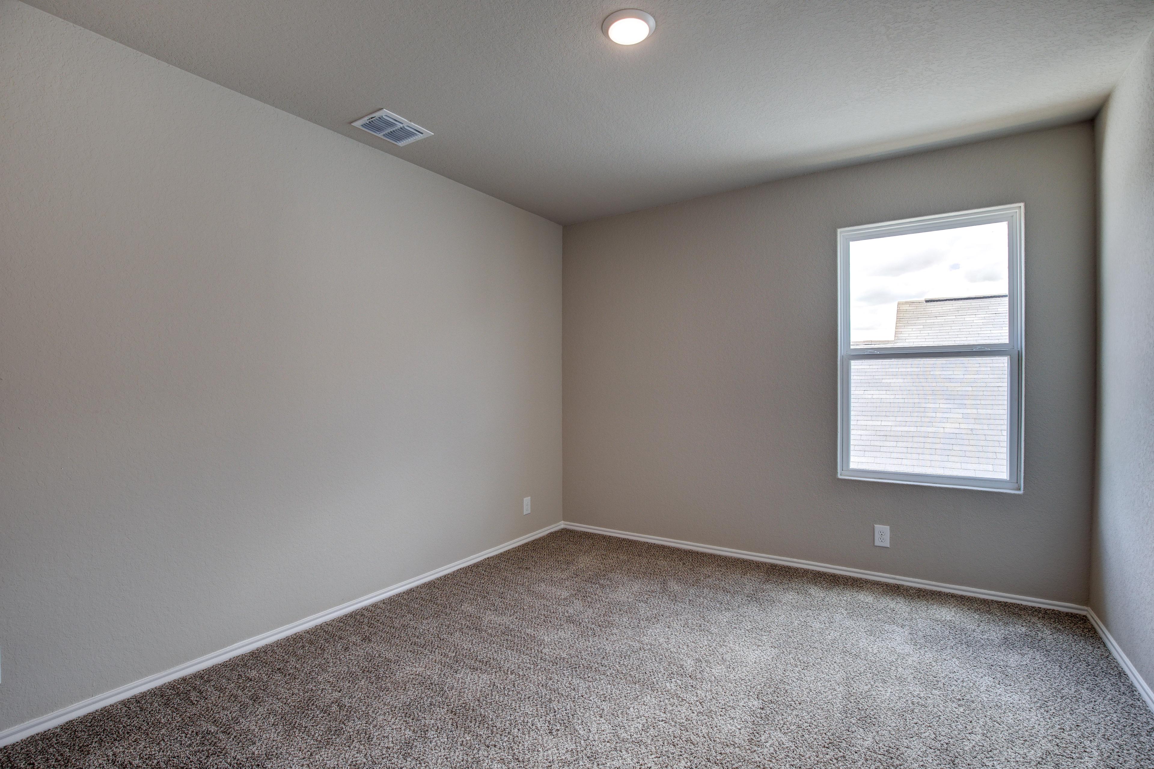 Spacious empty bedroom in The Murray G design with beige walls, carpet floor, large window, and recessed lighting