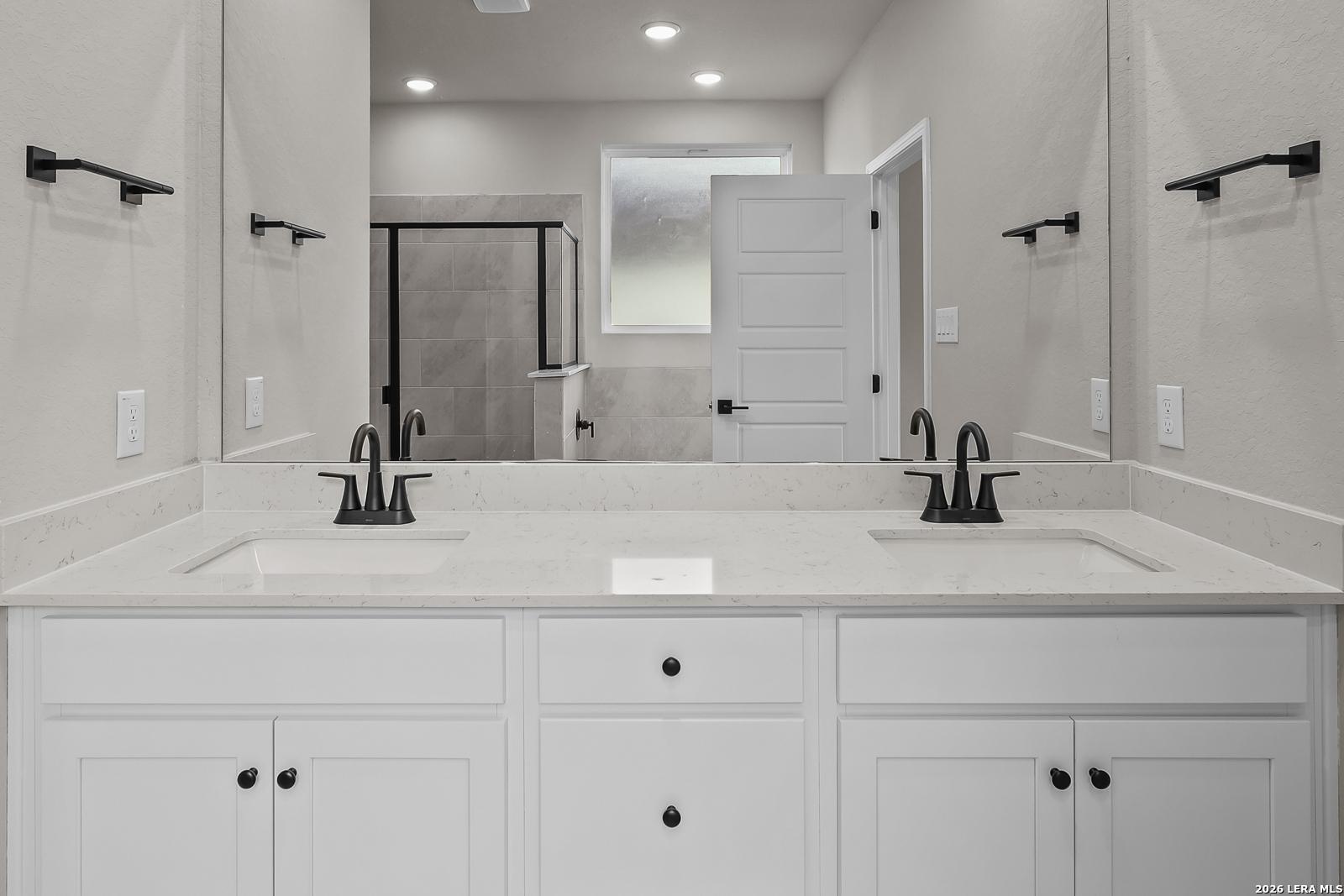 Double vanity bathroom with white cabinetry, quartz countertops, matte black fixtures in Davidson Homes Sequoia C, San Antonio