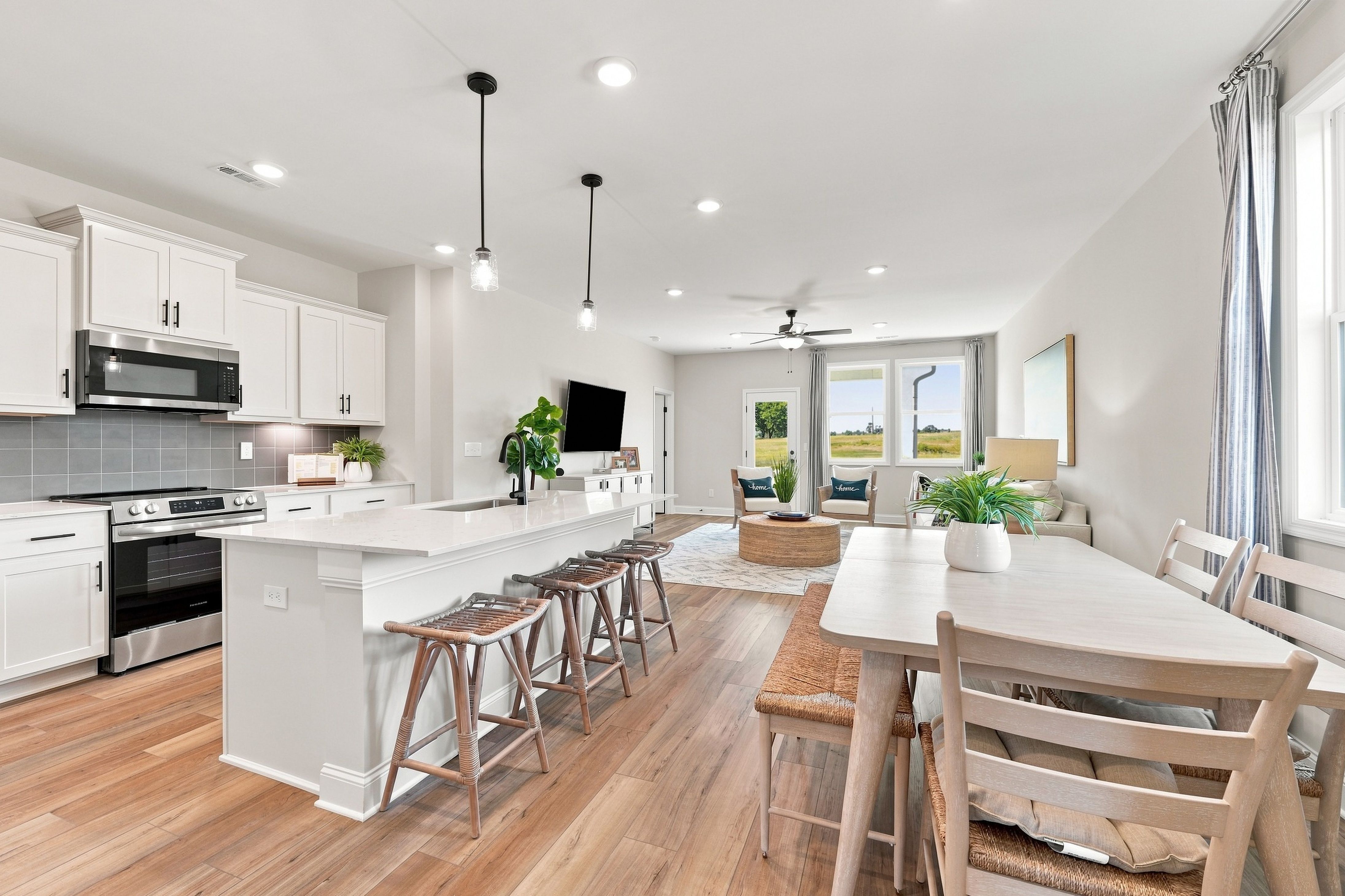 Open-concept kitchen and living area at Bailey Park in Fayetteville, TN featuring white cabinetry, kitchen island, and hardwood floors by Davidson Homes