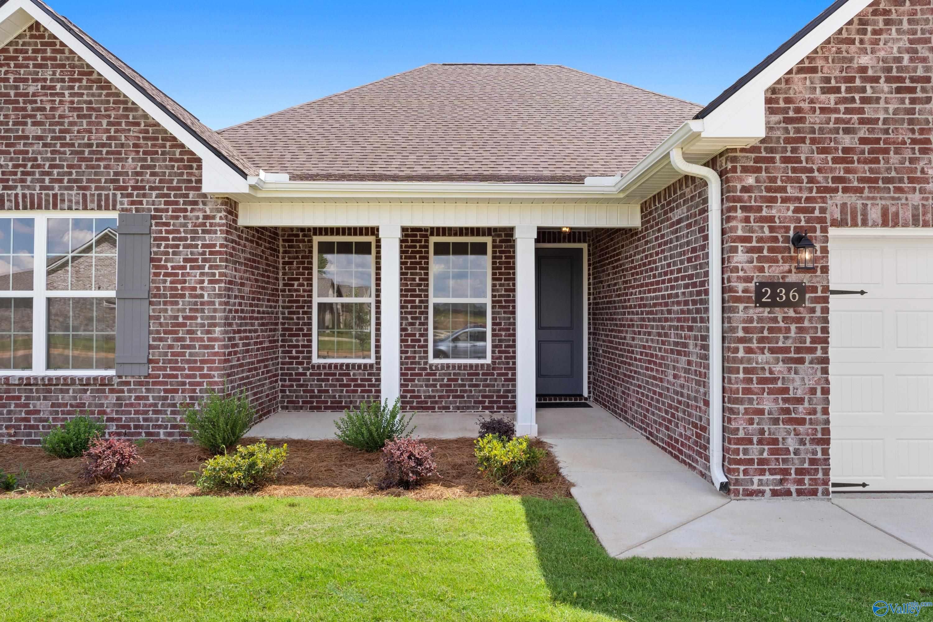 Modern red brick 1-story home with gabled roof, front porch columns, 2-car garage, and landscaped yard in Kendall Downs, Toney, Alabama