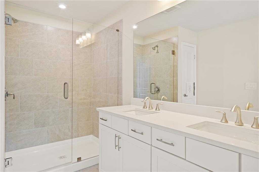 Modern master bathroom with frameless glass shower, double vanity, and tiled walls in Davidson Homes The Cary B, Kennesaw, Georgia