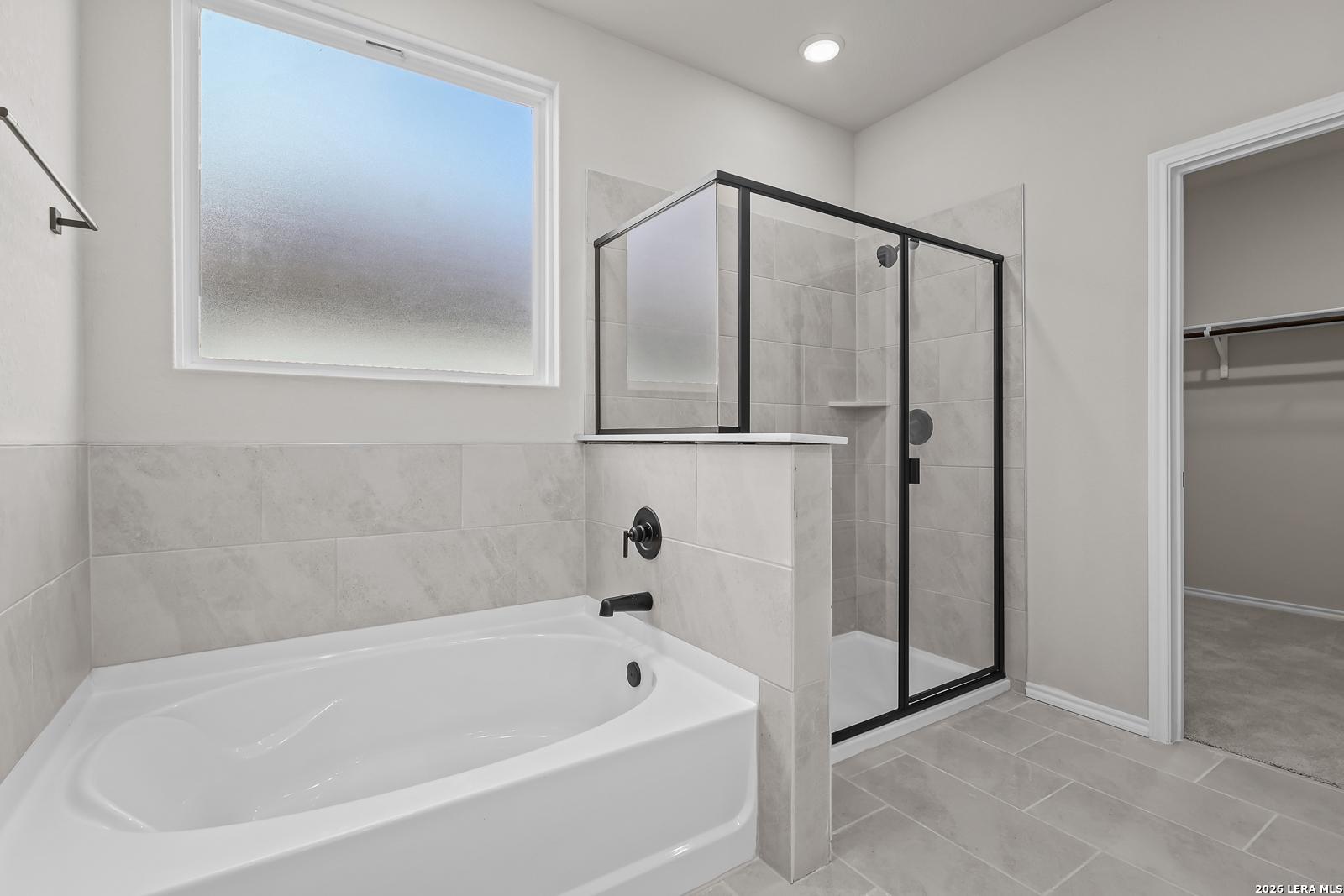 Modern master bathroom with soaking tub, glass walk-in shower, and frosted window in Davidson Homes The Sequoia C, San Antonio