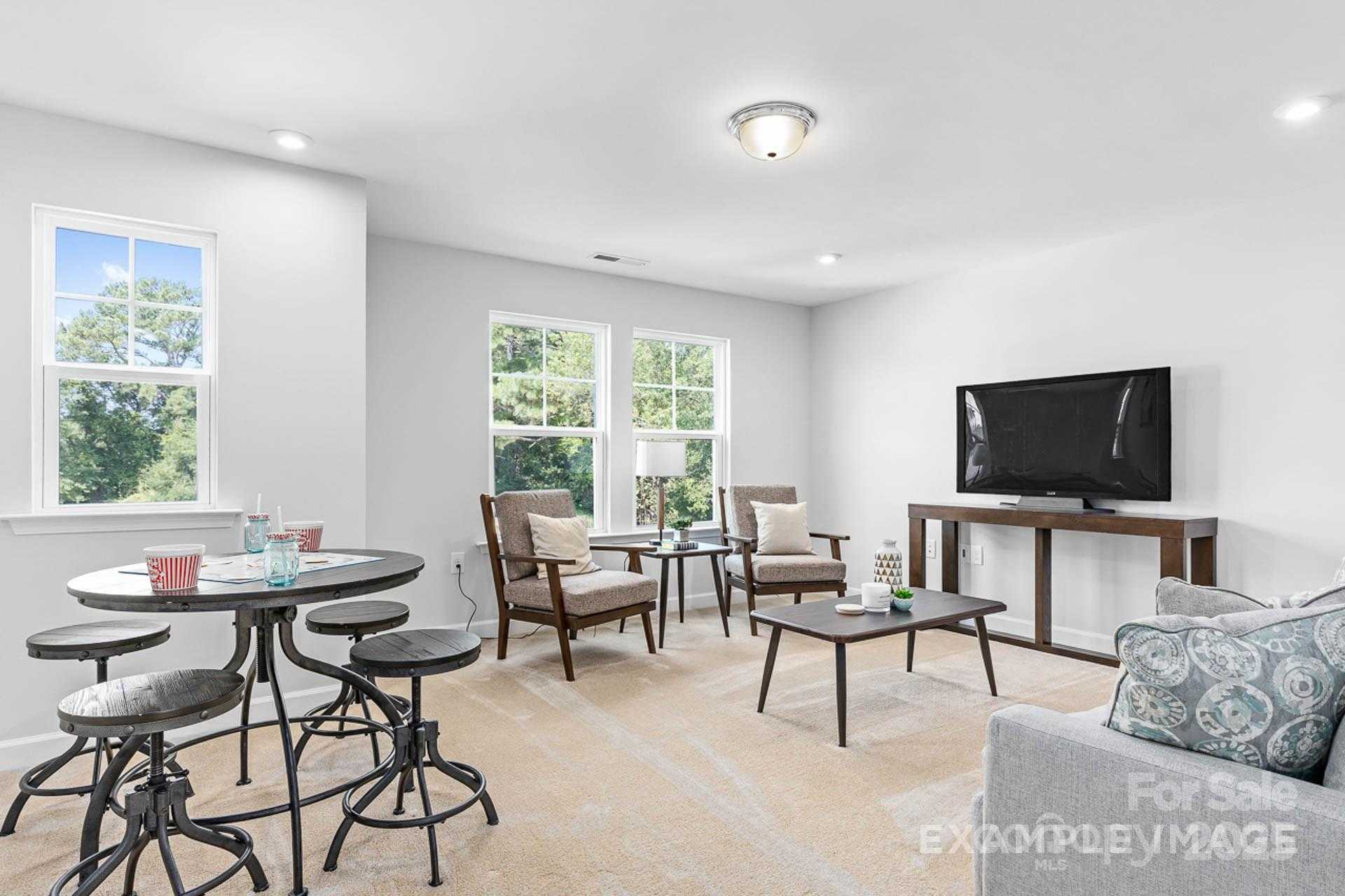 Cozy upstairs loft with gray sectional sofa, TV console, round pedestal table and armchairs in 4-bedroom Davidson Homes The Chestnut F, Belmont, NC