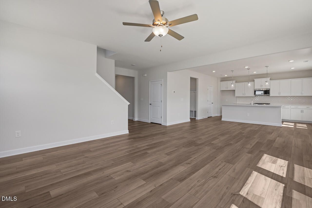 Open-concept living area with wood-look flooring and modern white kitchen in The Chestnut B home, Lillington, North Carolina.