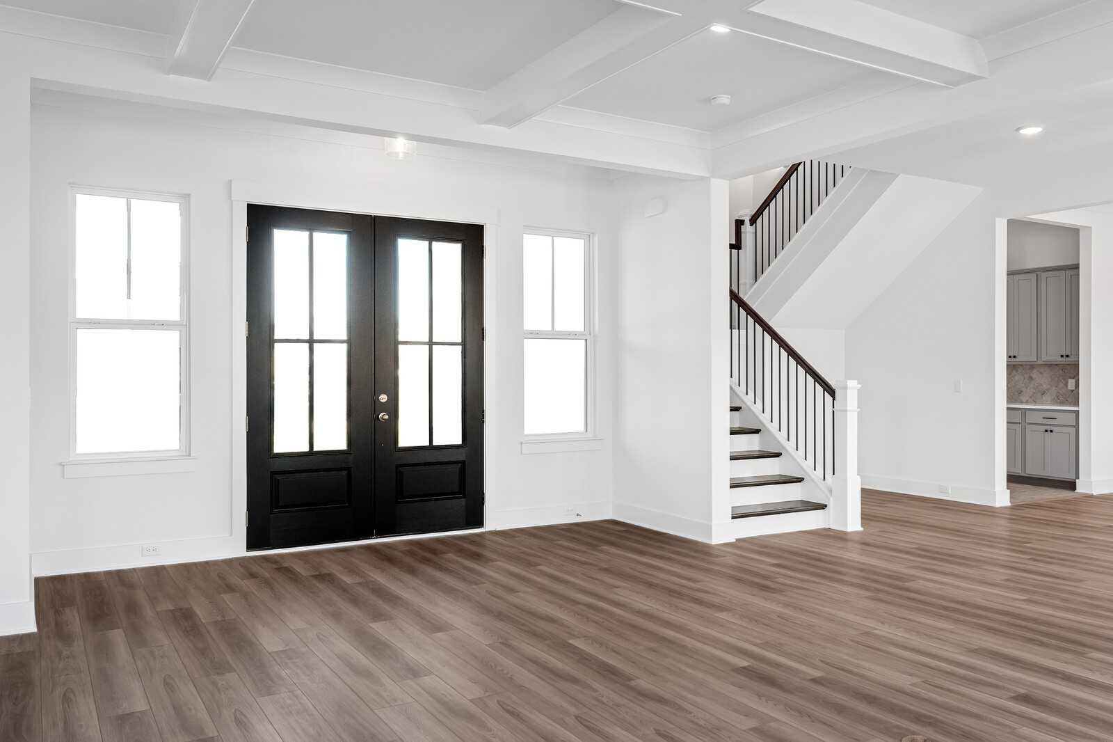 Grand entry foyer with black double doors, sidelight windows, oak staircase, and hardwood floors in Davidson Homes Alston A, Murfreesboro