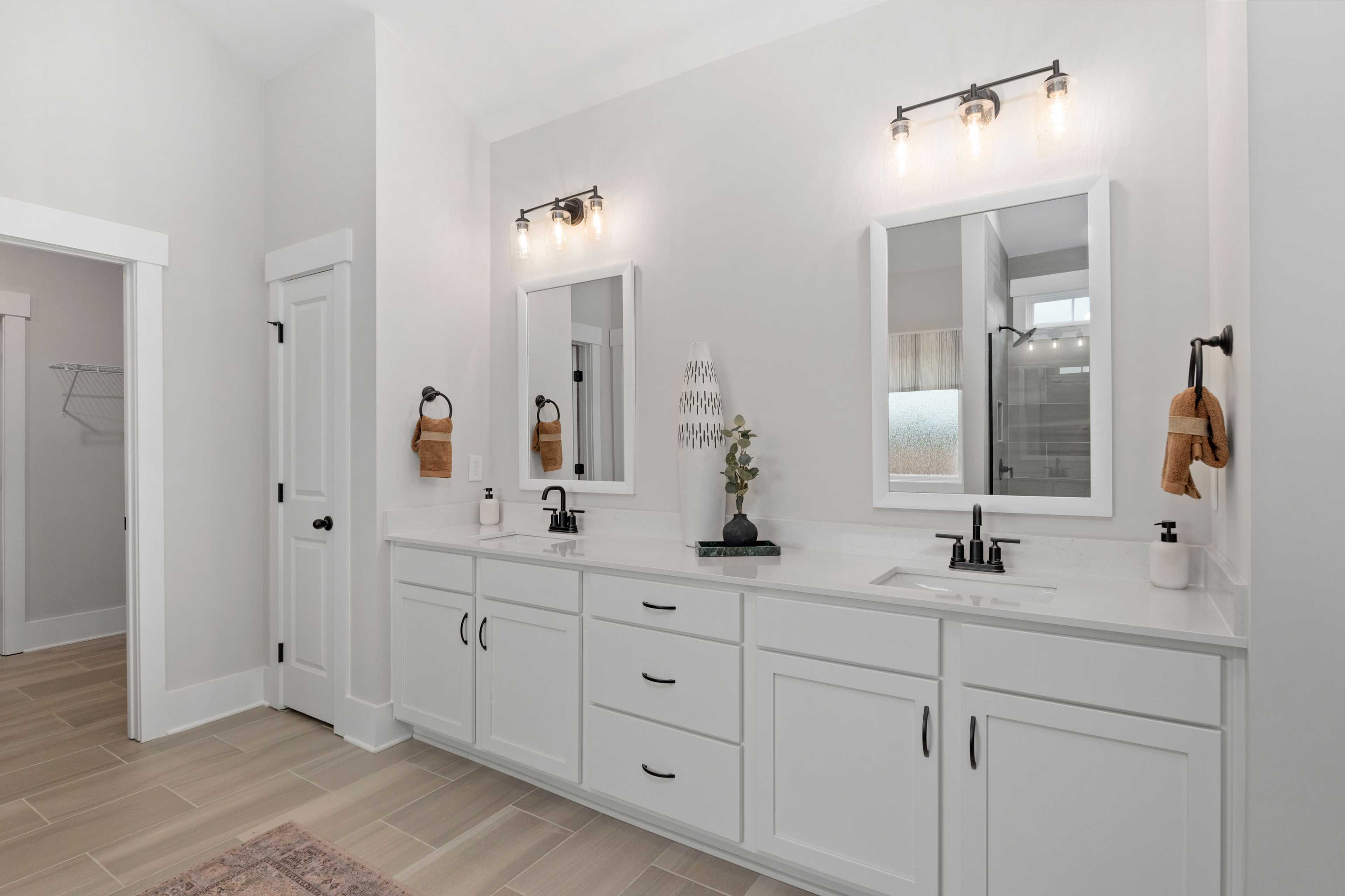 Spacious master bathroom at Briercreek in Meridianville AL with double white vanity, black sconces, mirrors, and walk-in shower