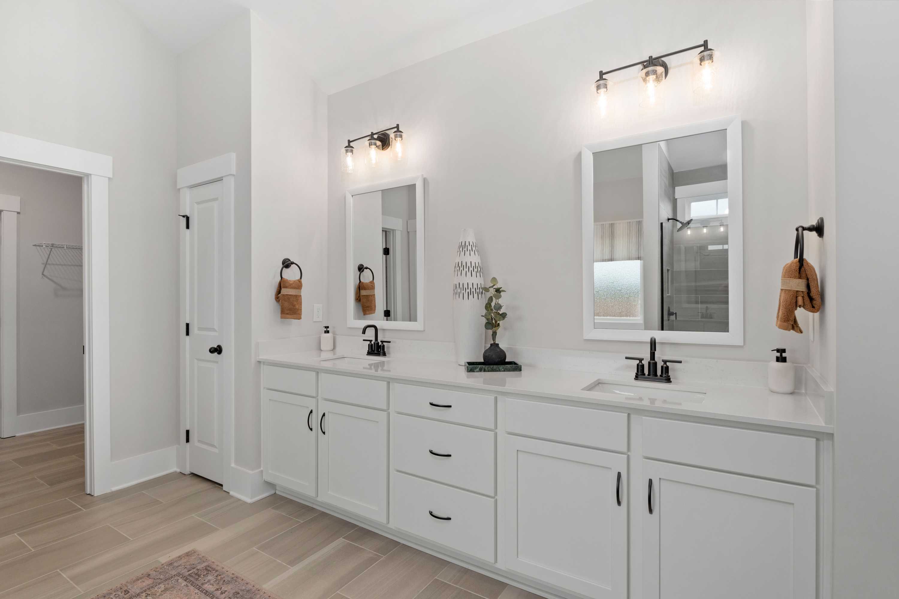 Spacious master bathroom at Briercreek in Meridianville AL with double white vanity, black sconces, mirrors, and walk-in shower