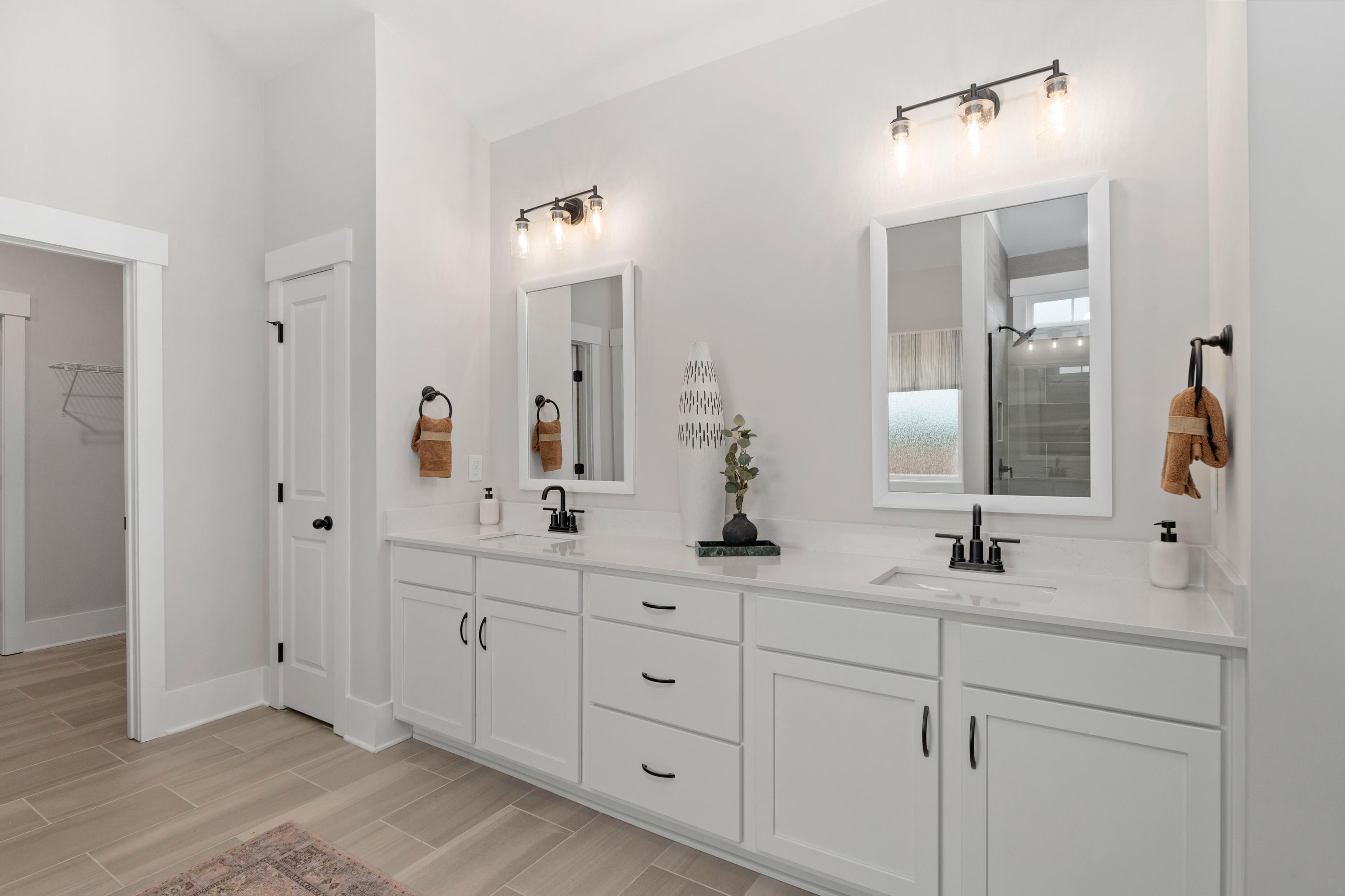 Spacious master bathroom at Briercreek in Meridianville AL with double white vanity, black sconces, mirrors, and walk-in shower