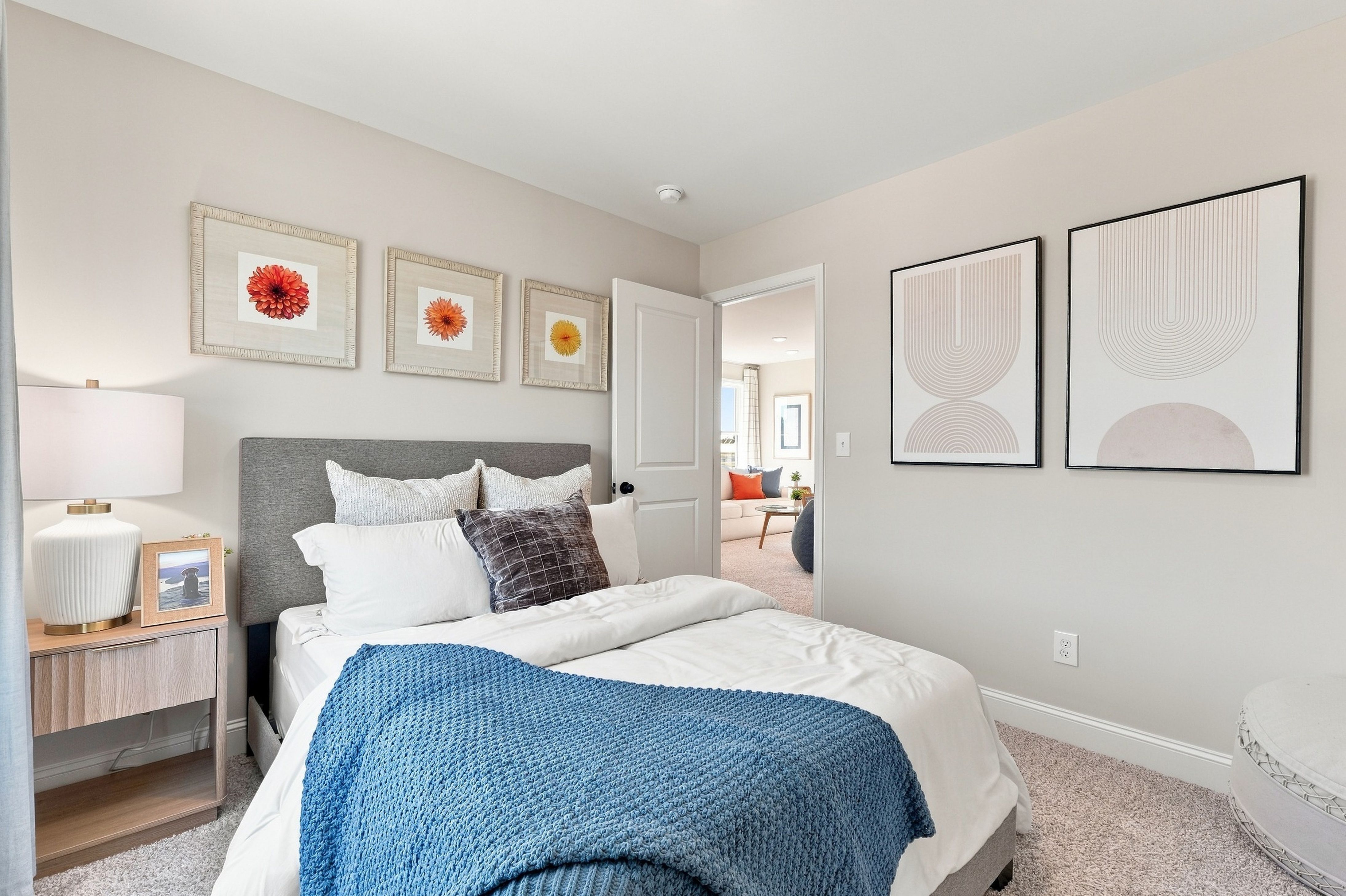 Bright model bedroom at Bailey Park in Fayetteville, Tennessee by Davidson Homes with gray upholstered headboard and blue accent blanket