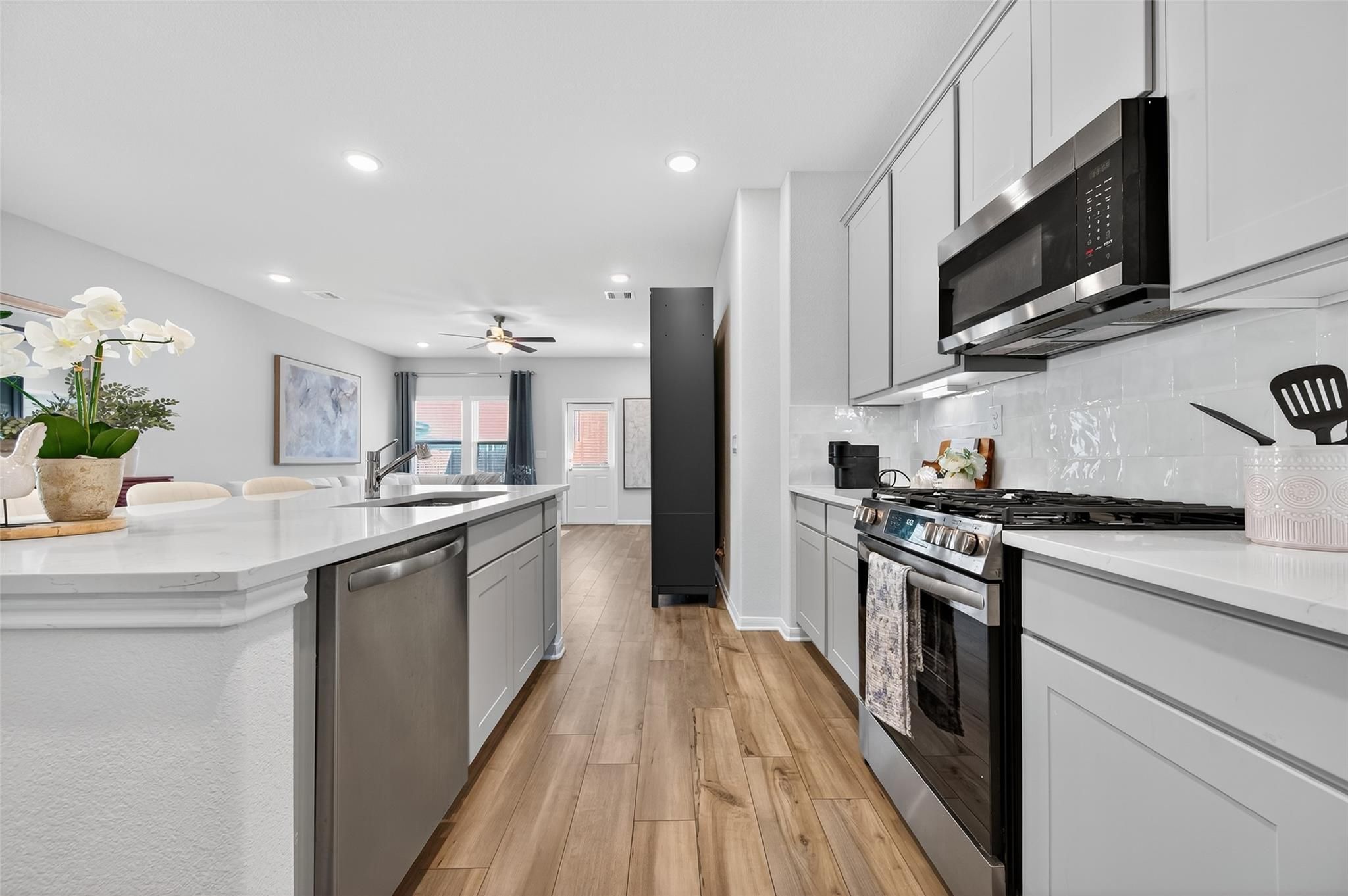 Modern open-concept kitchen with white shaker cabinets, quartz island, stainless appliances in Davidson Homes The Brazos E, Magnolia TX