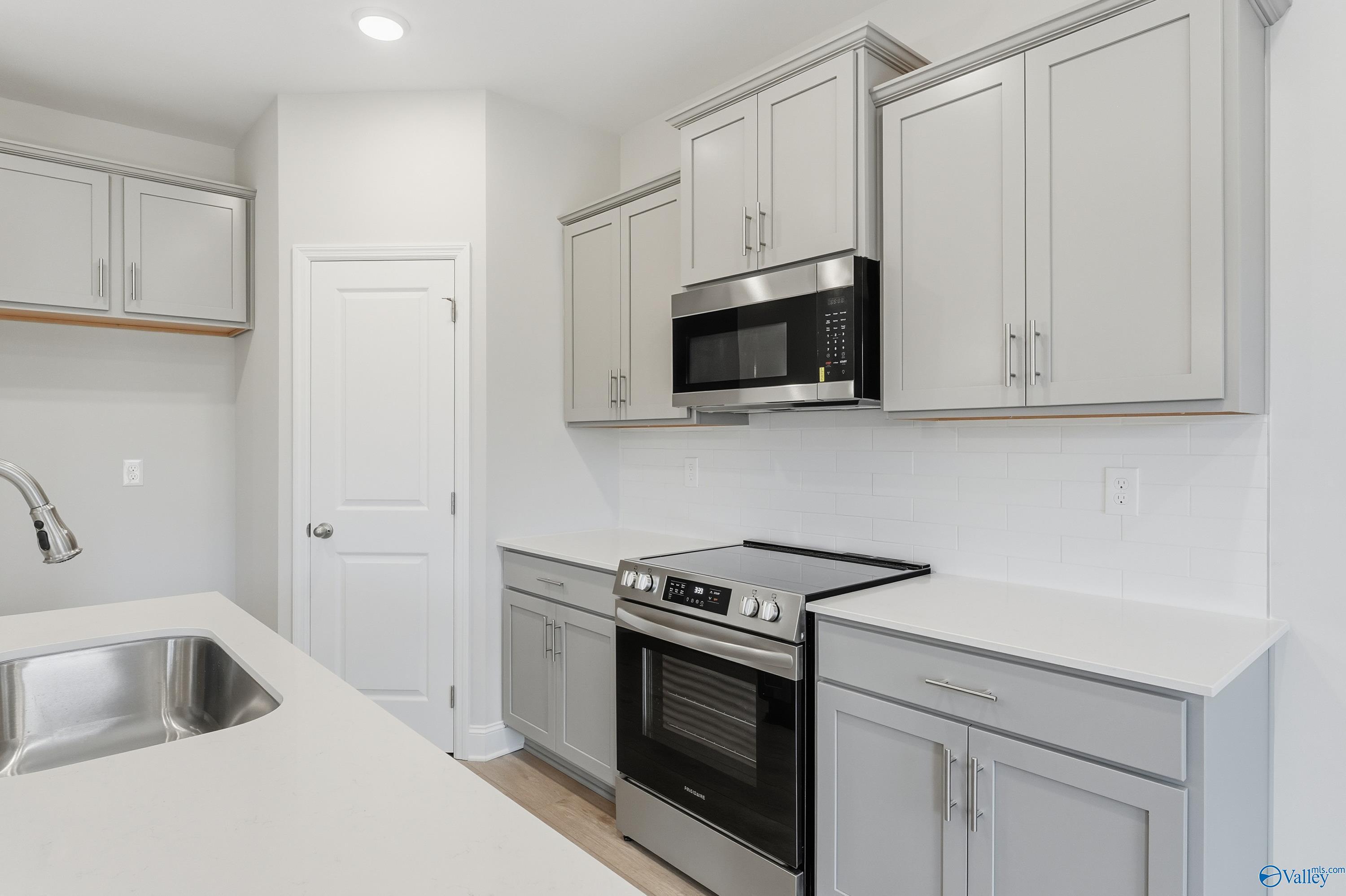 Modern kitchen featuring white cabinets, stainless steel appliances, and quartz island in Davidson Homes The Butler, Toney, Alabama