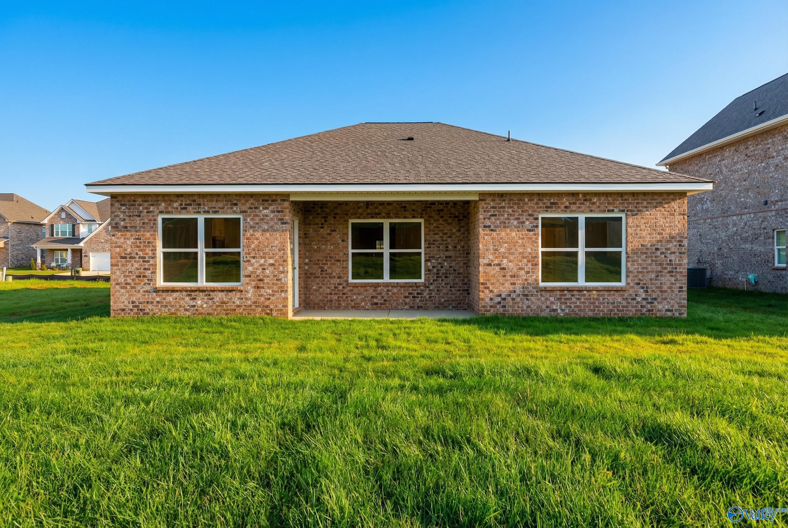 Front view of brick single-story home with gabled roof, covered entry, and triple windows on lush green lawn in Walker's Hill, Meridianville, Alabama
