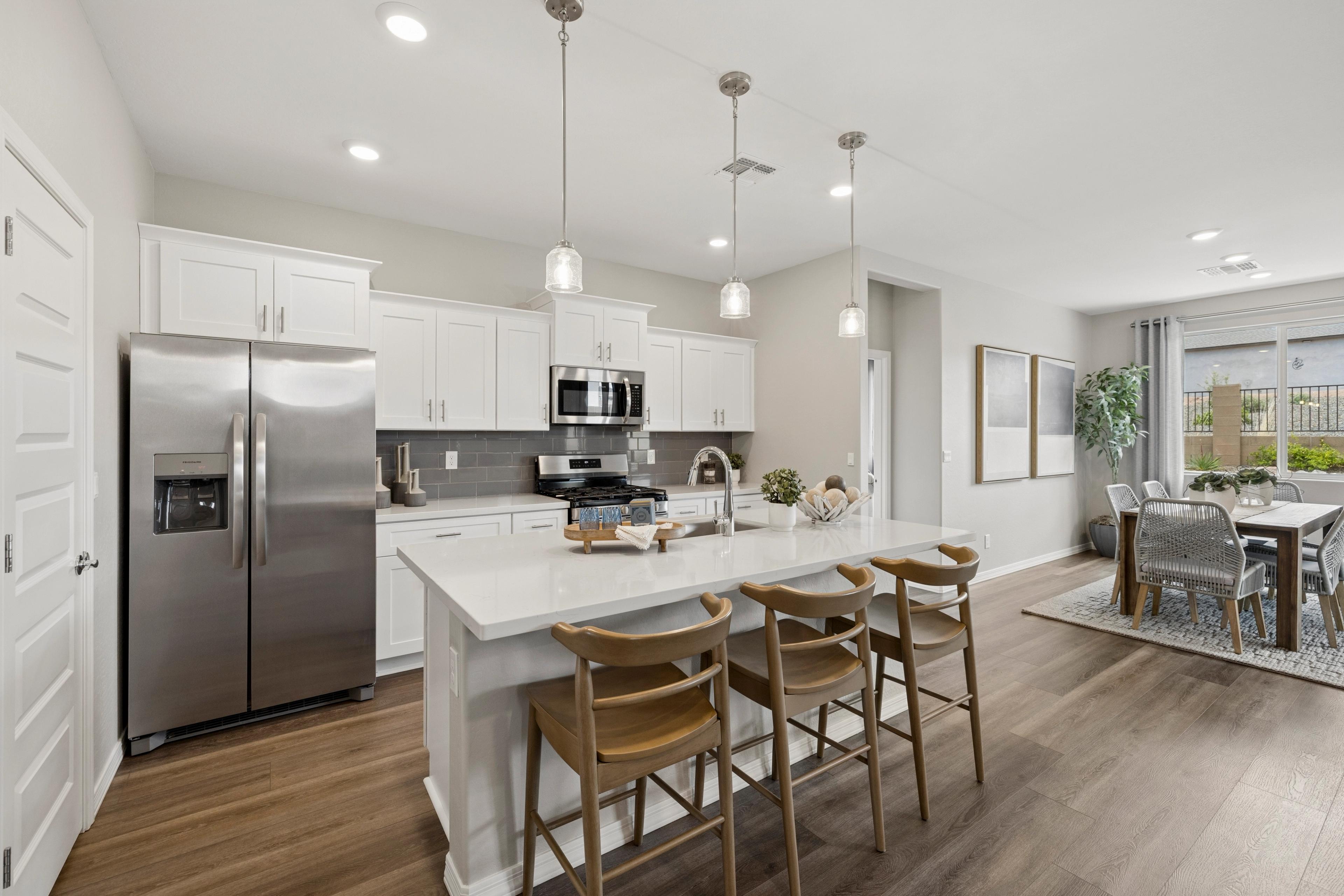 Spacious kitchen at South Ranch Destination Collection in Prescott AZ with white cabinets quartz island wood stools stainless appliances and dining area