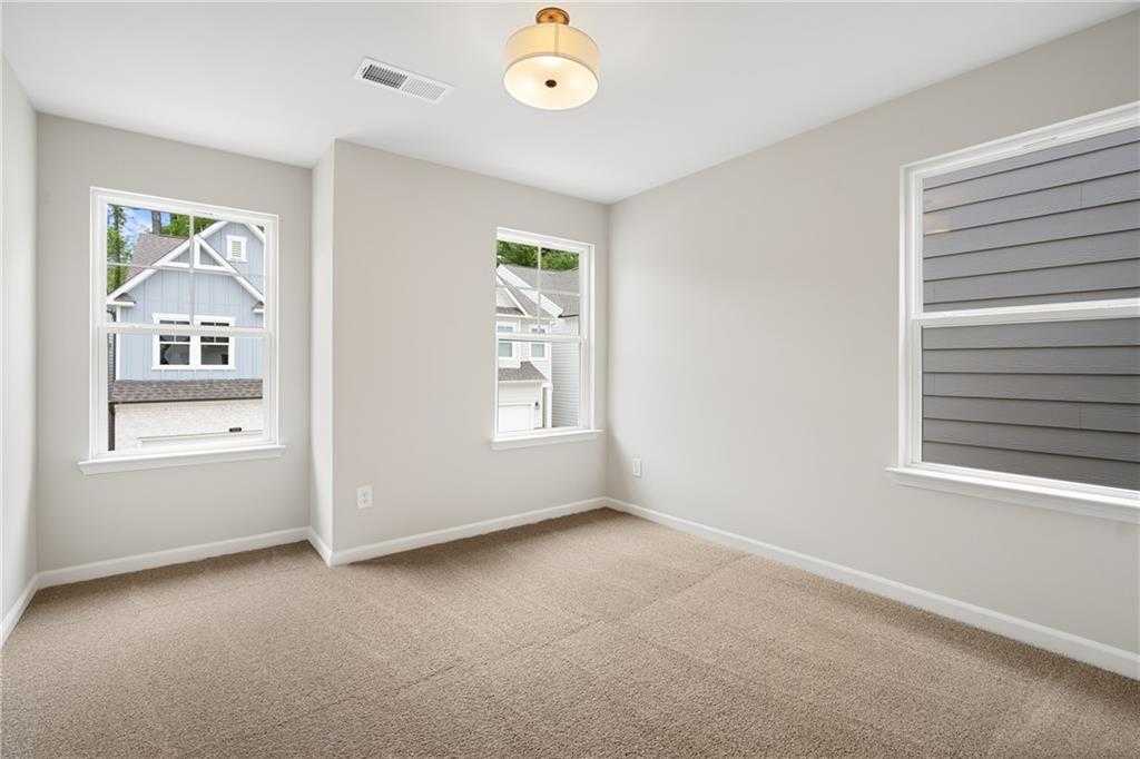 Bright secondary bedroom with light gray walls, beige carpet, and large windows in Davidson Homes The Marion A, Kennesaw, GA