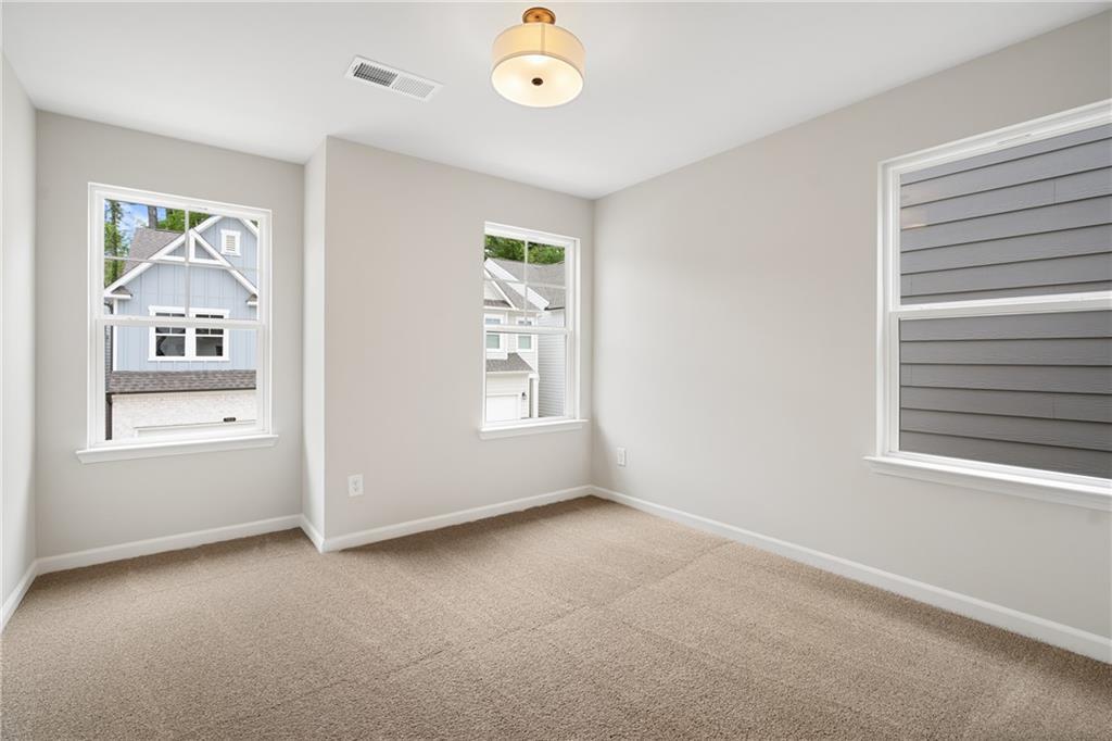 Bright secondary bedroom with beige carpet, gray walls, and large windows in Davidson Homes The Marion A, Kennesaw, GA