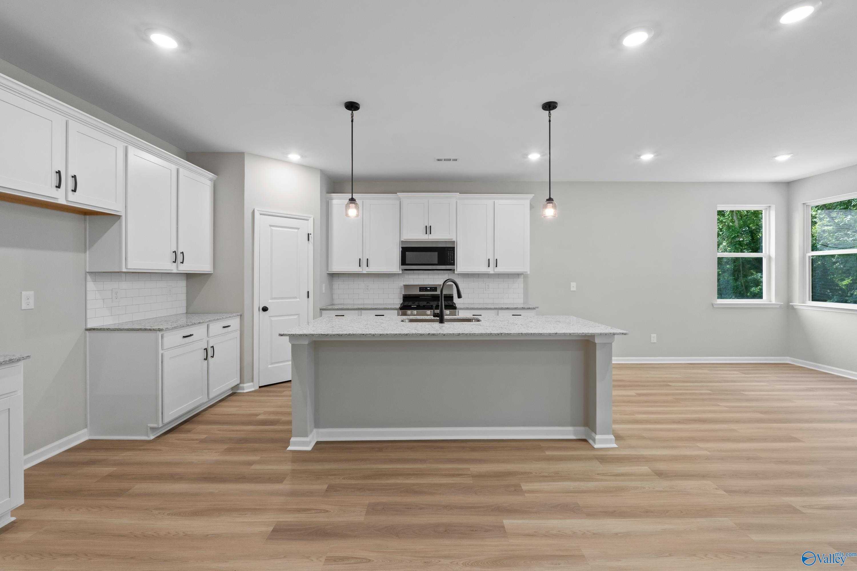 Modern white shaker kitchen with quartz island, stainless appliances, pendant lights in Davidson Homes The Phoenix, Hazel Green, AL